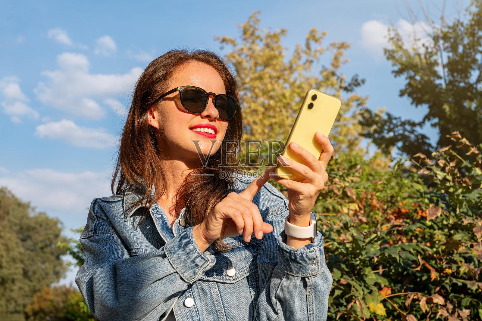 城市女性在户外使用智能手机。在线消息、点击购买、在线租赁。照片摄影图片