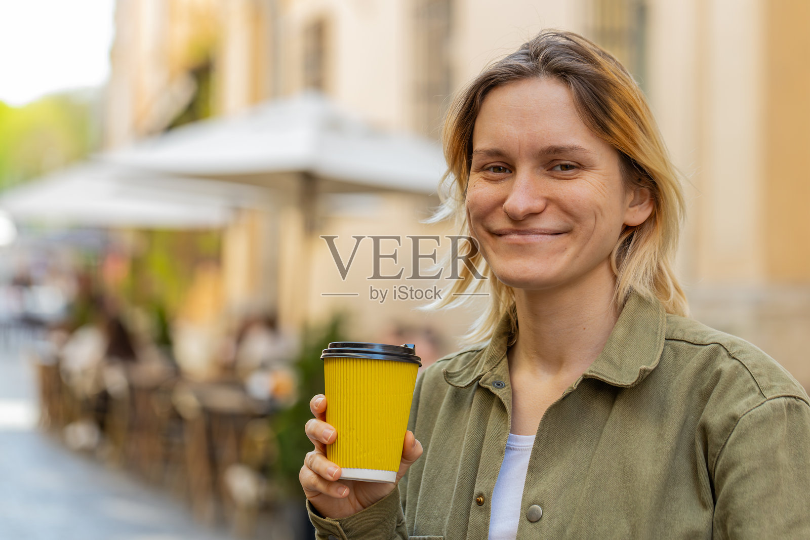 微笑的女性在城市街道上走着，享受着热咖啡，放松心情，休息片刻。照片摄影图片