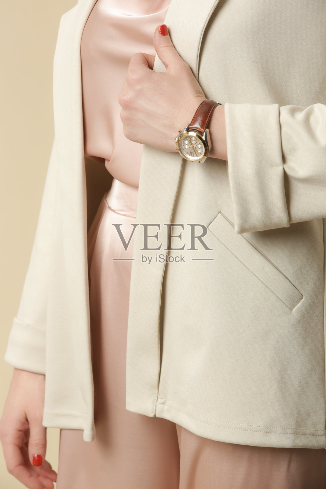 女性模特穿着奶油色西装外套，搭配淡粉色丝绸服装。经典简约的时尚。摄影棚拍摄。照片摄影图片