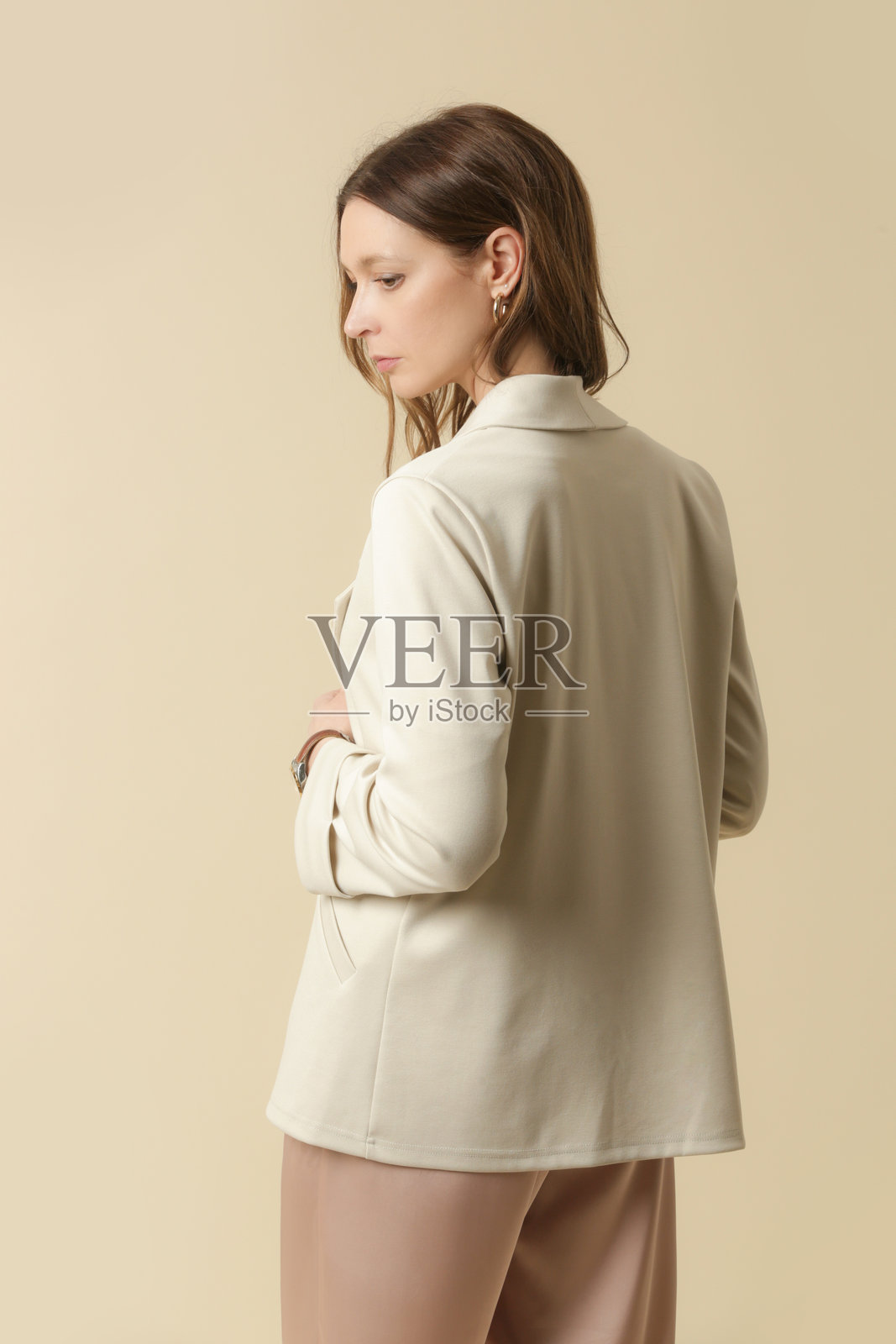 女性模特穿着奶油色西装外套，搭配淡粉色丝绸服装。经典简约的时尚。摄影棚拍摄。照片摄影图片