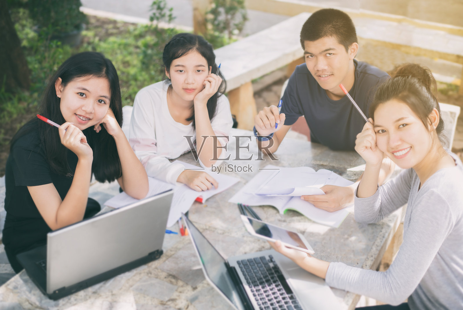 微笑的学生们在户外坐着学习的肖像照片摄影图片