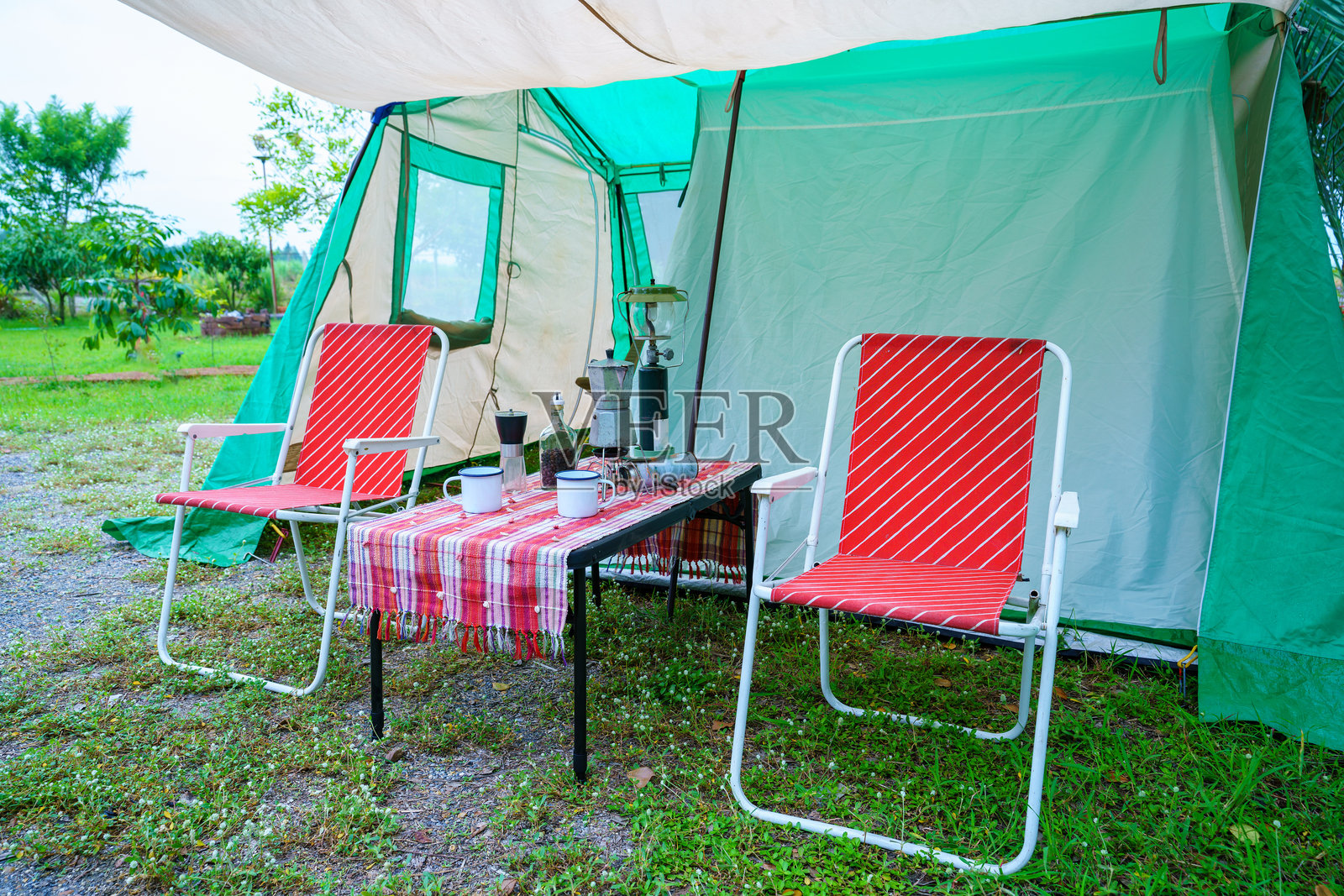 复古咖啡具在旧木桌上的特写，前方是复古帐篷、复古椅子、一组露营帐篷，以及柔和的焦点。照片摄影图片