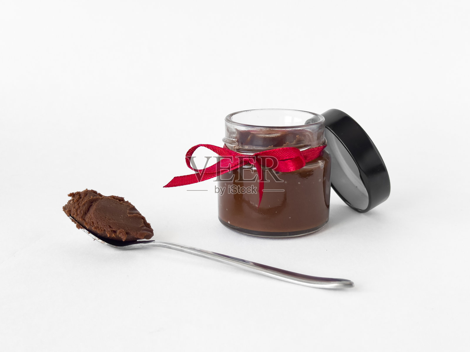 优雅罐装的美食巧克力酱，配有红色丝带和勺子照片摄影图片