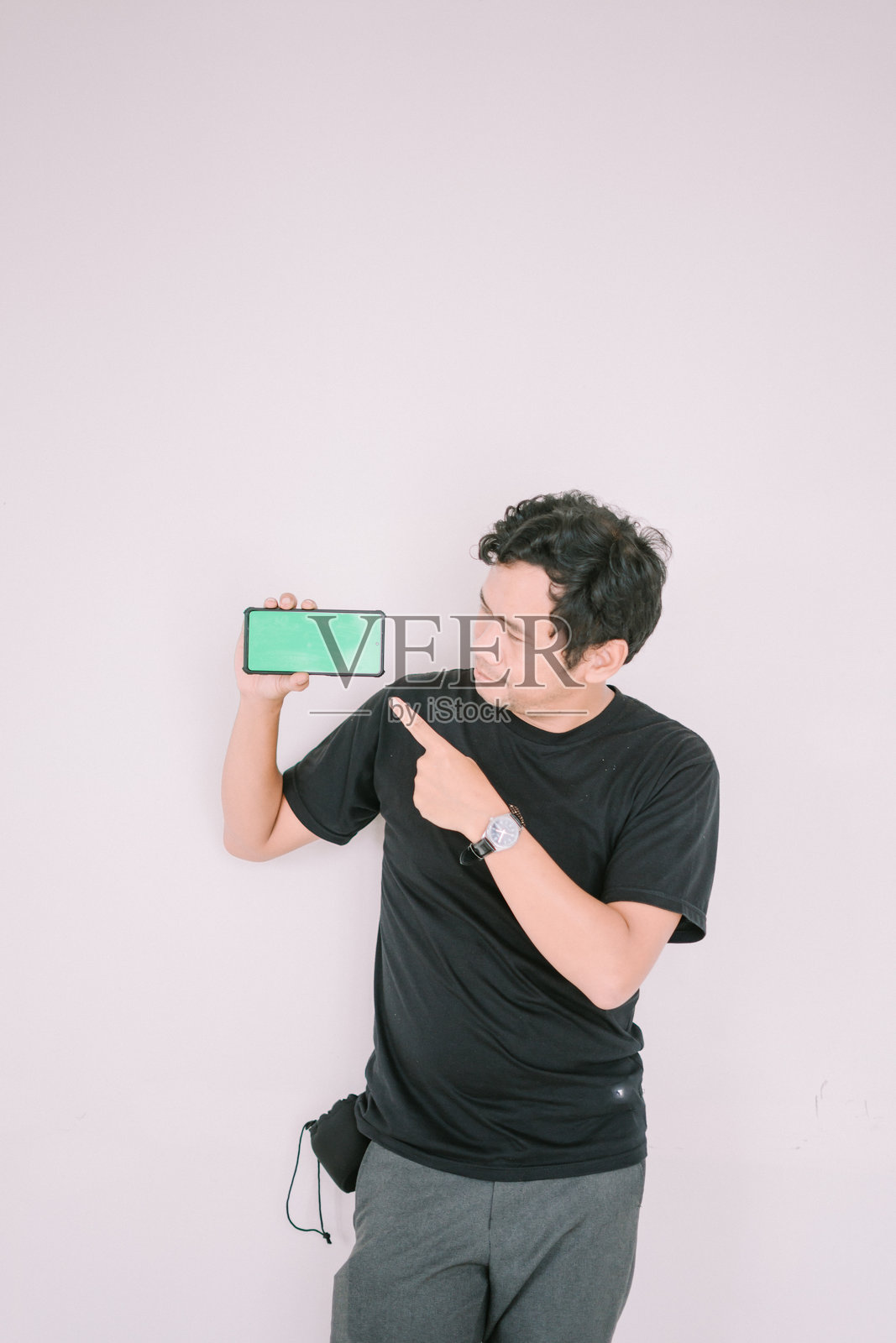 一名男子手持绿幕手机，指向摄像头。照片摄影图片