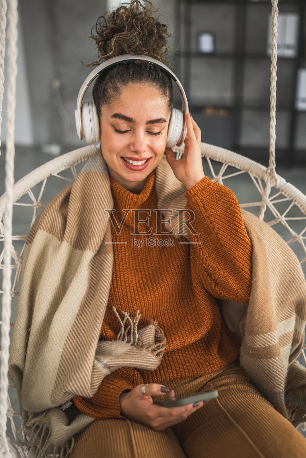 一位在家戴着耳机听在线音乐的女性，面带微笑。照片摄影图片