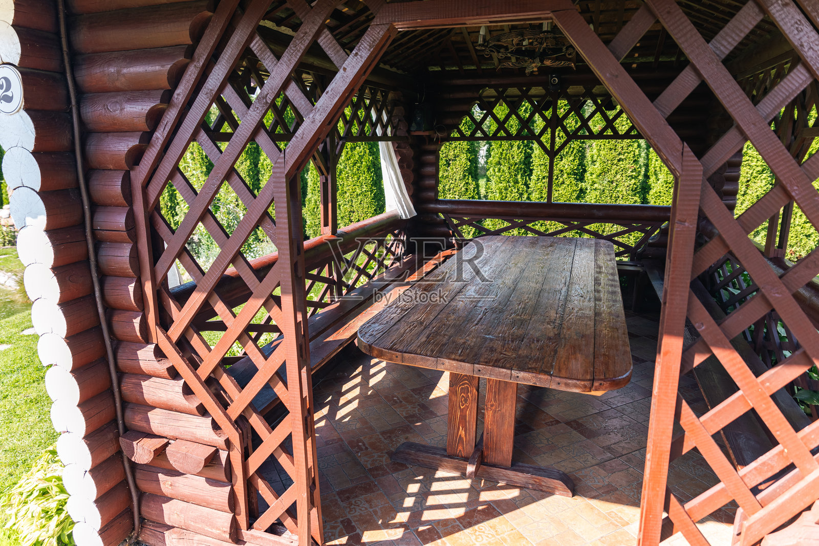 凉亭内的木桌和长椅。桌子和长椅由天然木材制成，营造出温暖而宜人的氛围。桌子是矩形的，表面光滑且略显磨损。照片摄影图片