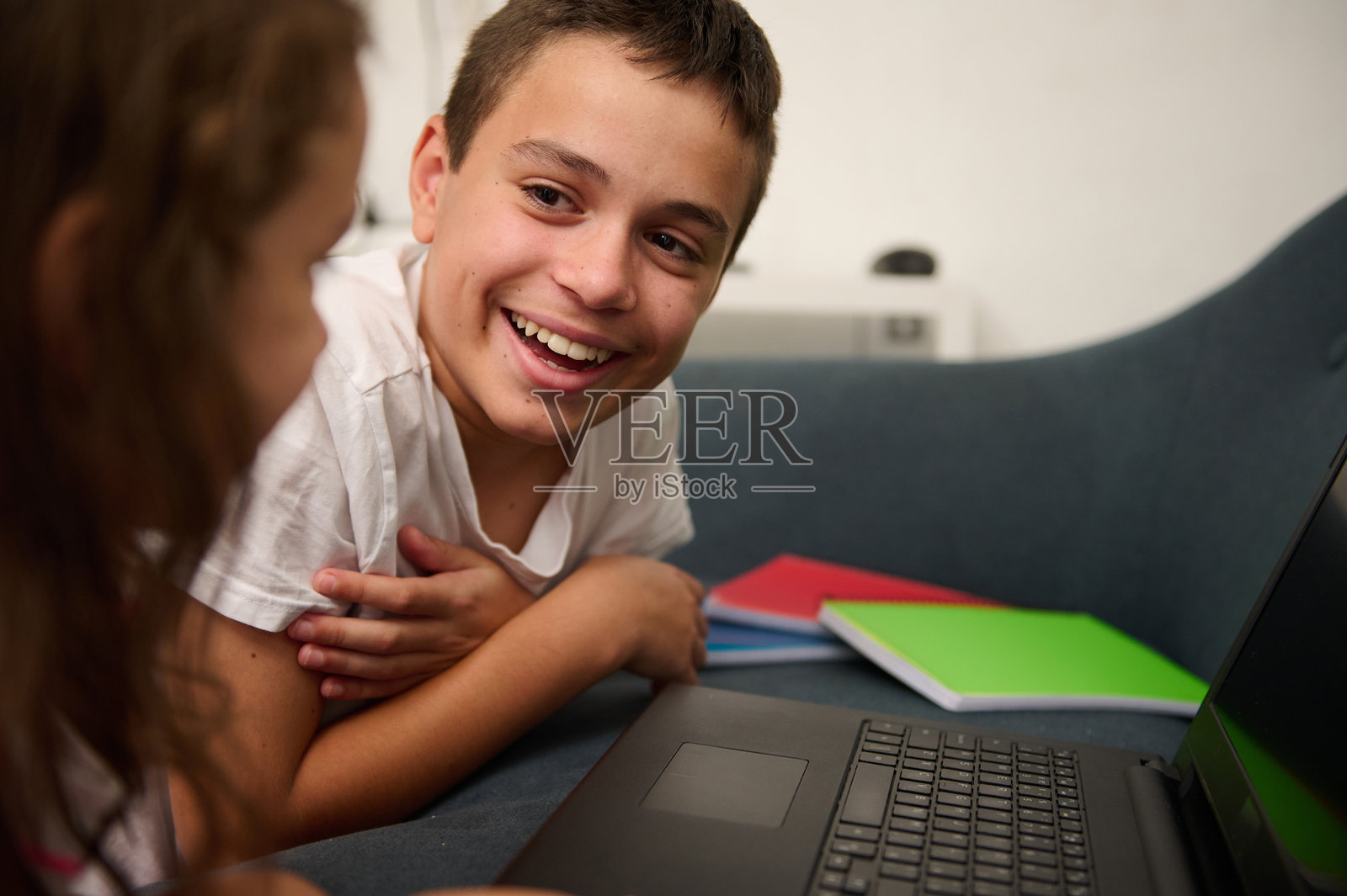 快乐的男孩在家里用笔记本电脑与妹妹互动照片摄影图片