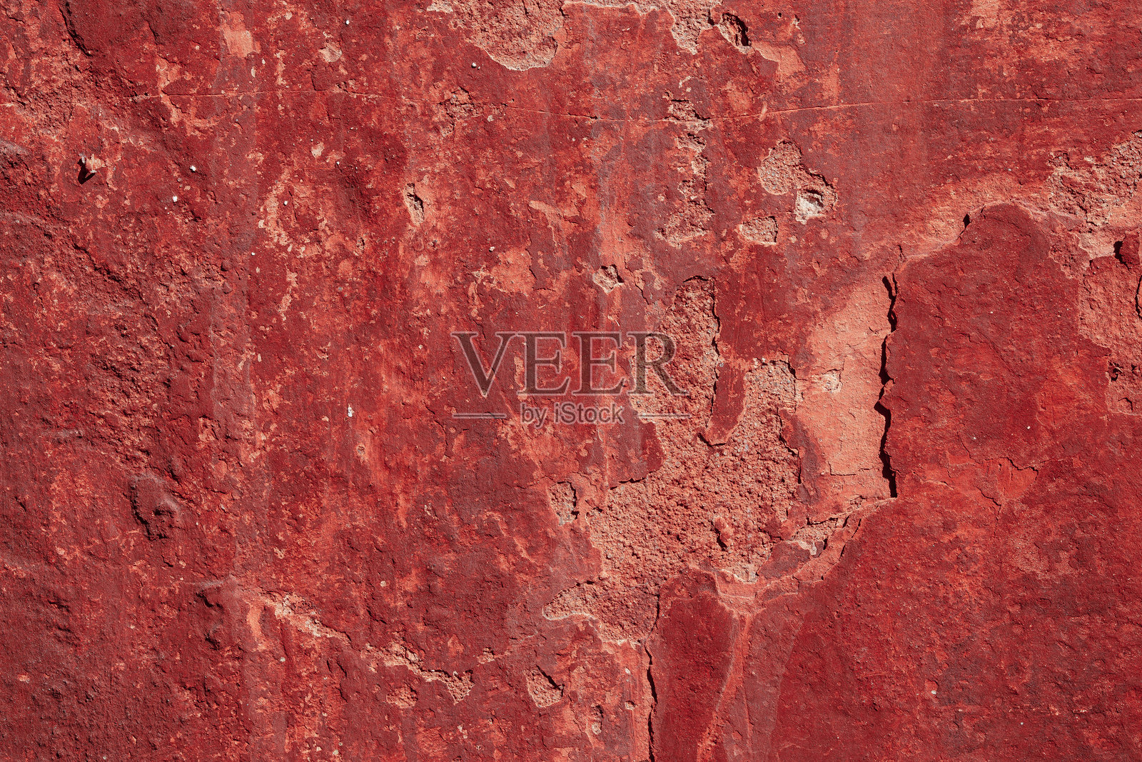 红色混凝土墙面有深深的划痕和缺口。各种磨损的变化。照片摄影图片