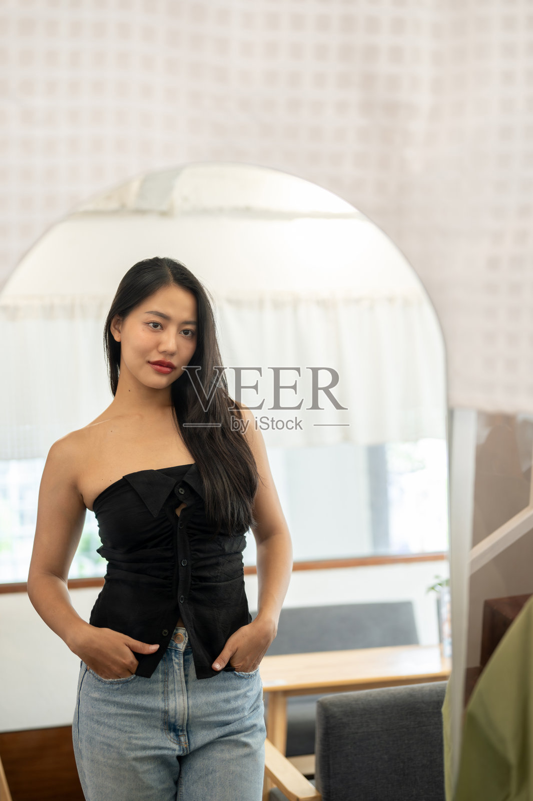 一位迷人的亚洲女性在室内镜子前自信地欣赏自己。照片摄影图片