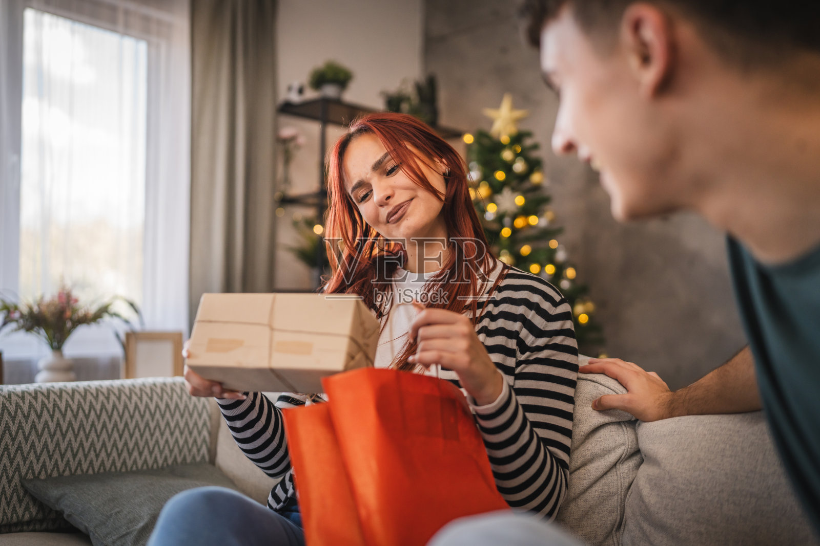 男朋友在家里把购物袋里的圣诞礼物送给女朋友照片摄影图片