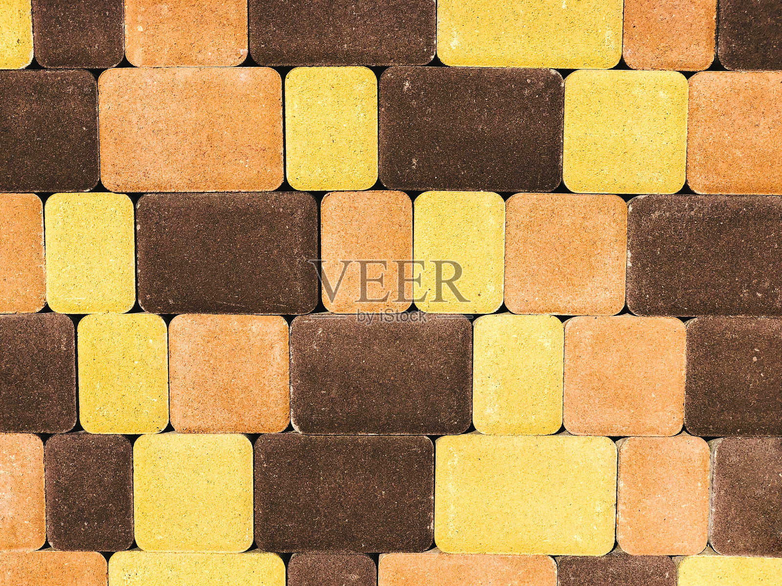 棕色、黄色和橙色三色铺路石的背景，图案照片摄影图片