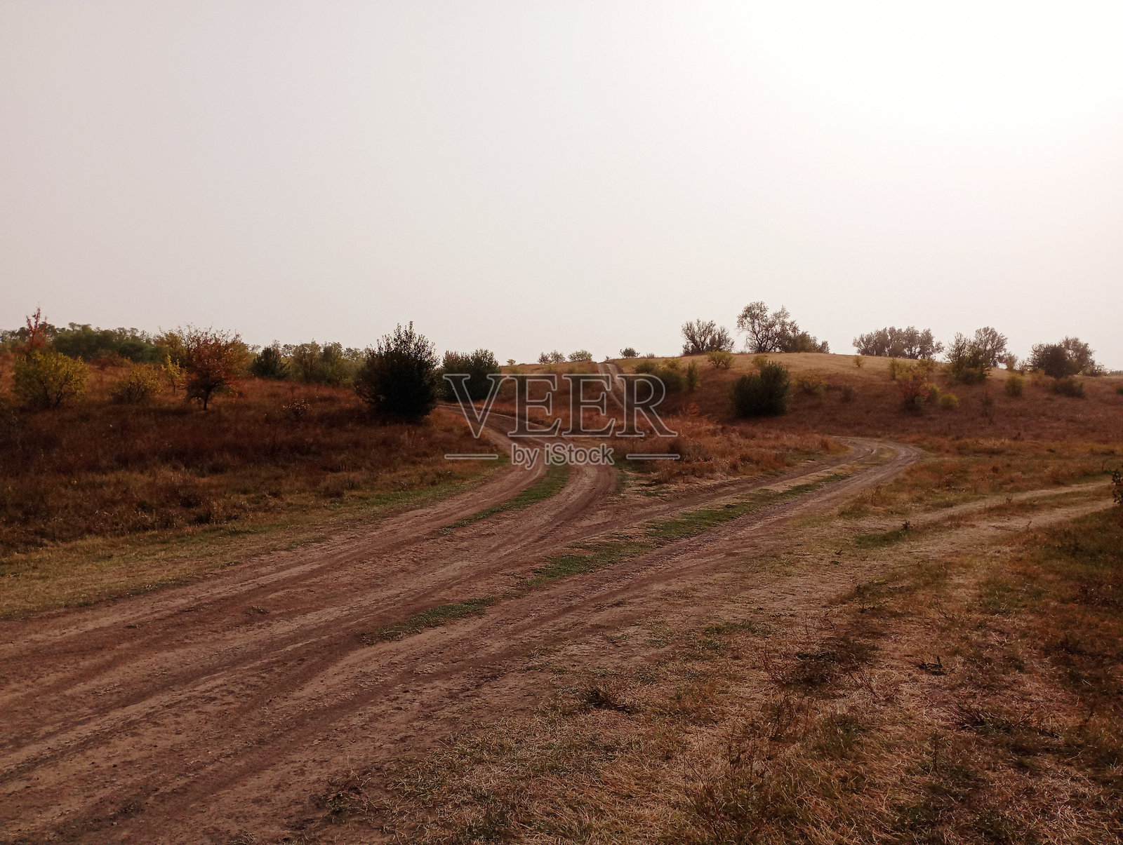 丘陵和尘土飞扬的田间小路交错延伸，通向地平线的风景。美丽的秋季景观。照片摄影图片