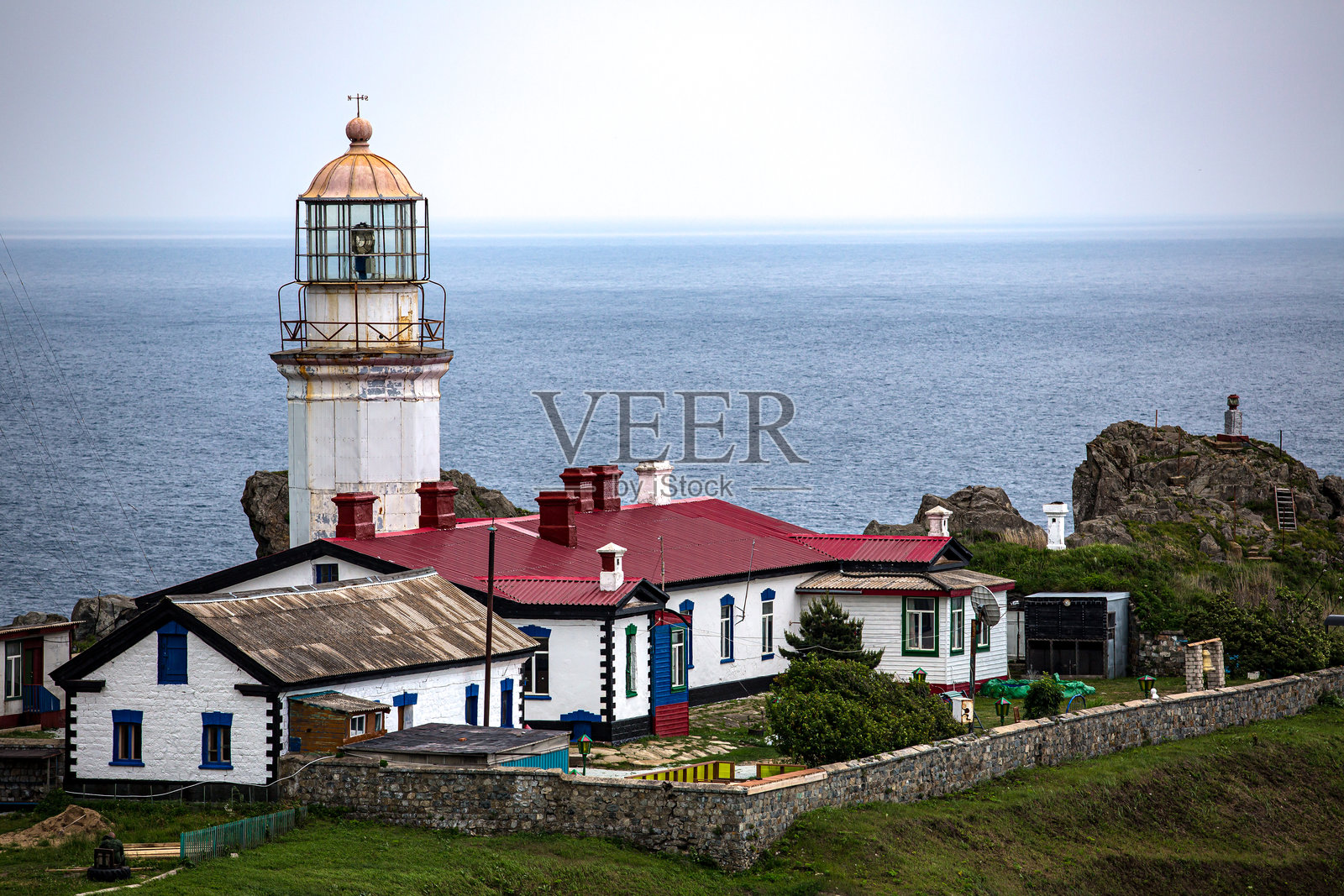 一座红屋顶的灯塔矗立在海边的山丘上照片摄影图片