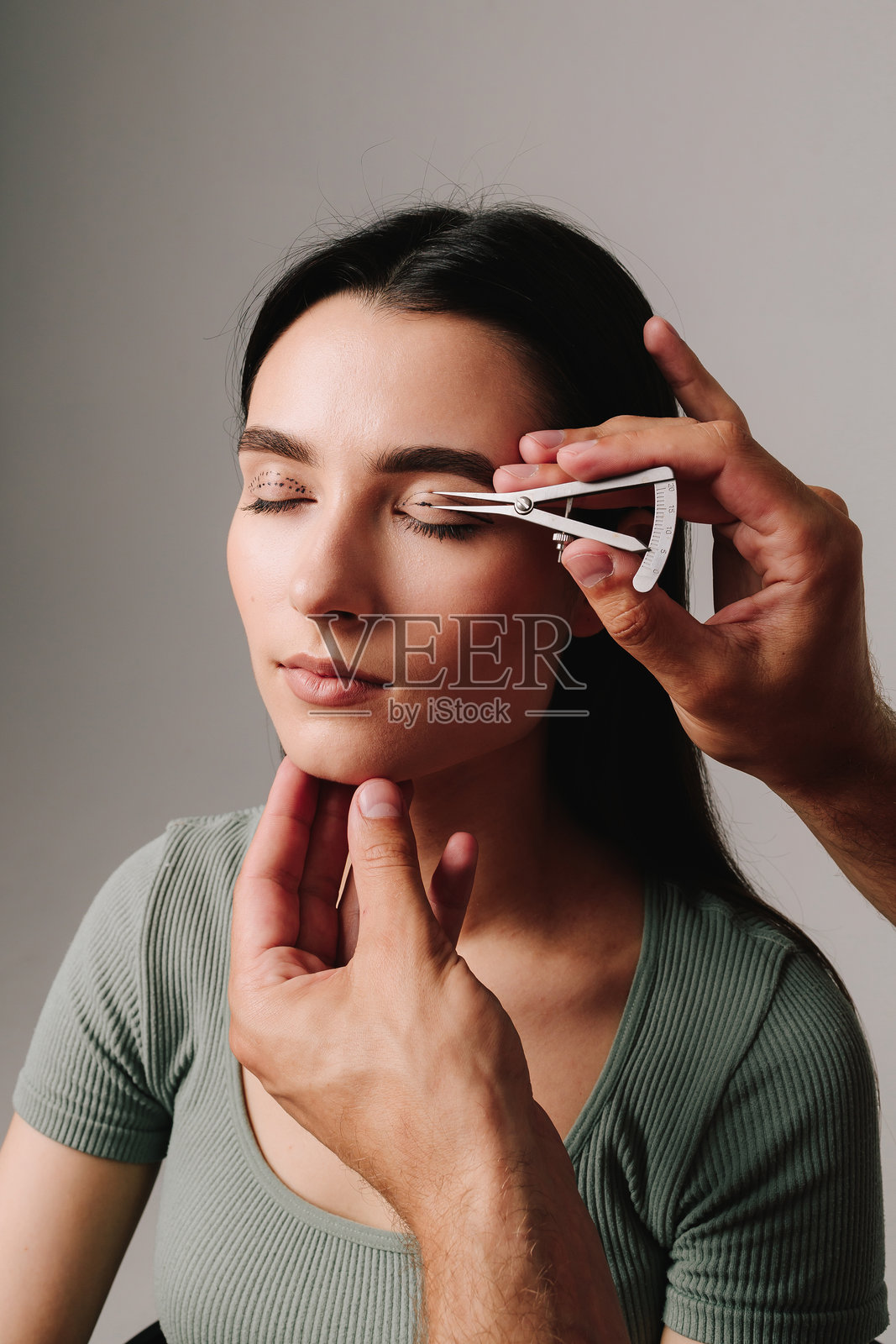 Castroviejo卡尺用于绘制眼睑手术的对称轮廓。眼睑成形术标记。整形外科医生正在测量标记线之间的距离，以便进行精心规划的眼睑成形术。照片摄影图片