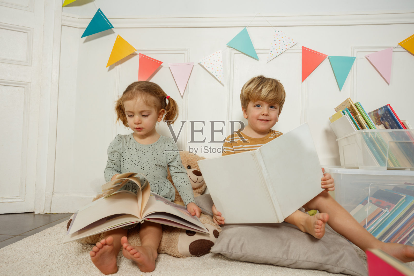 两个兄弟姐妹在温馨多彩的卧室里一起阅读书籍照片摄影图片