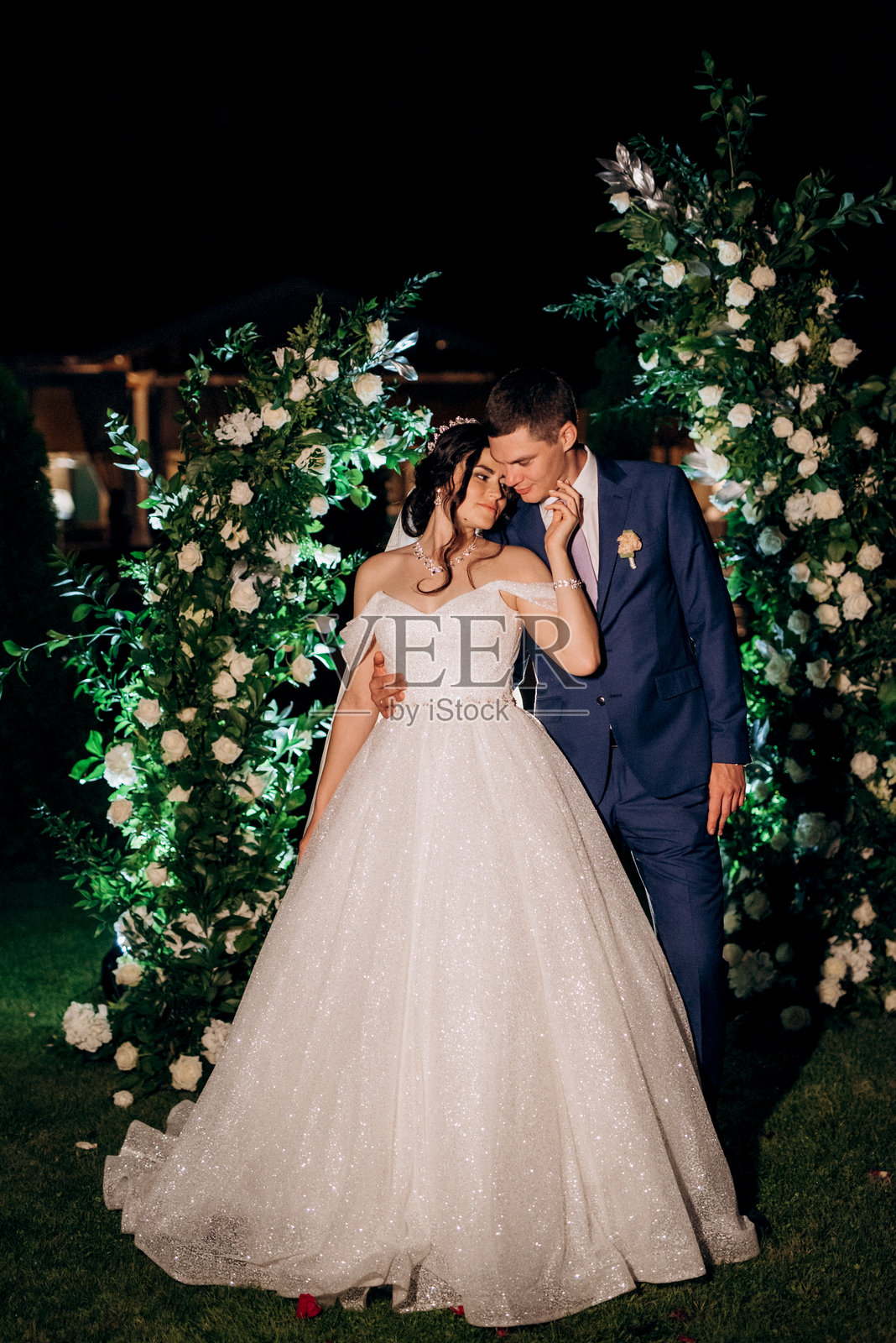 女孩和男孩在夜晚婚礼拱门的背景下照片摄影图片