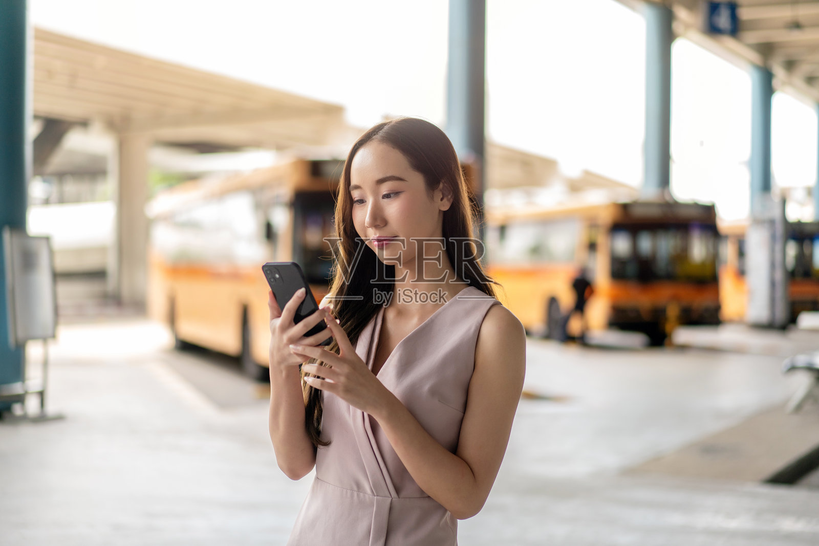 年轻女性在公交车站使用智能手机进行移动银行业务照片摄影图片