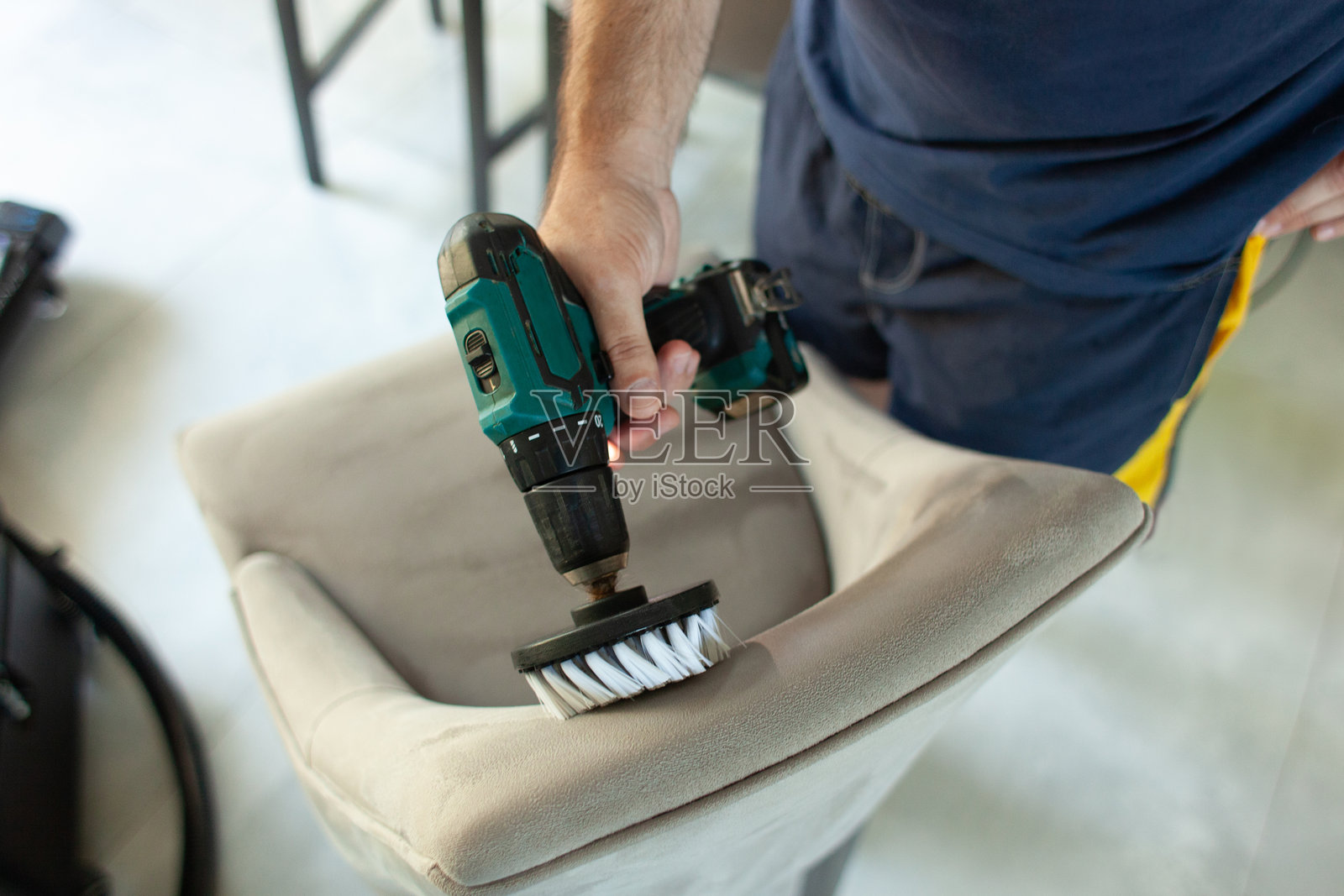 一名干洗工人在室内用刷子和螺丝刀清除椅子上的污垢。照片摄影图片