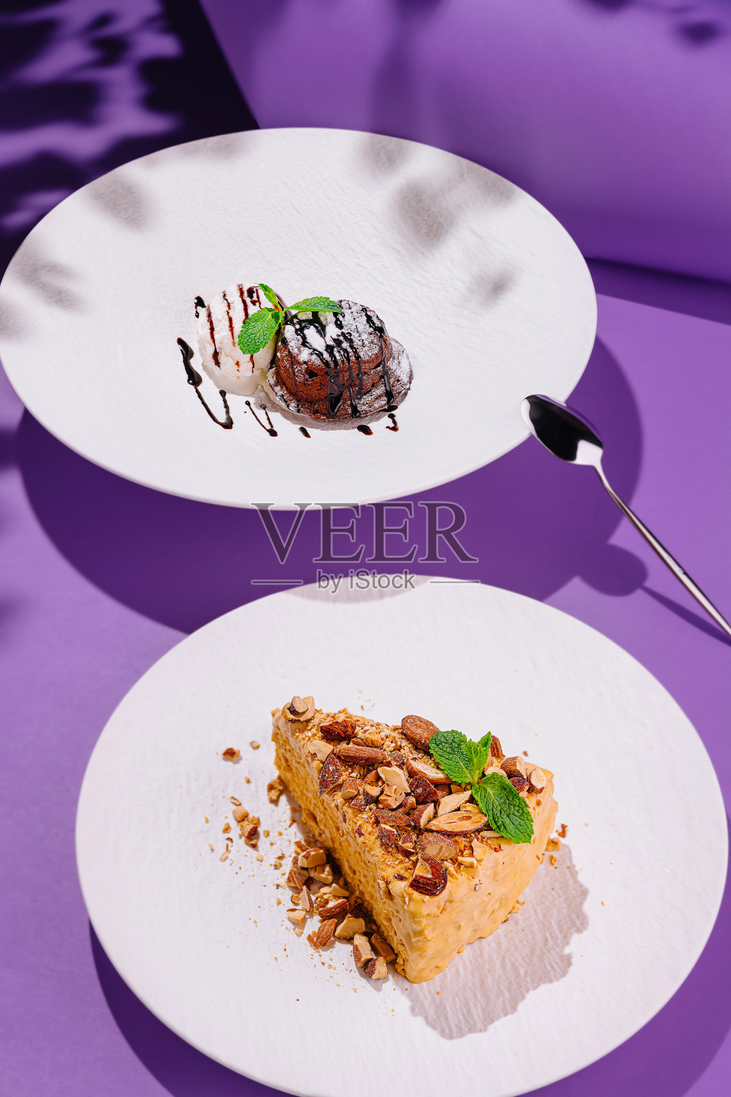 两款美味的甜点摆放在现代紫色背景上，形成鲜明的阴影对比。照片摄影图片