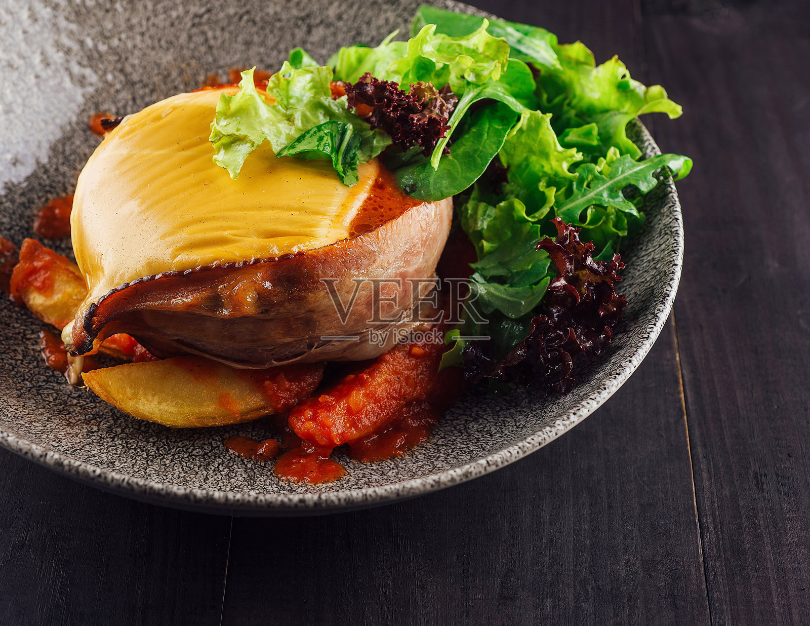 奶酪和培根填充的鸡胸肉放在灰色盘子上。照片摄影图片