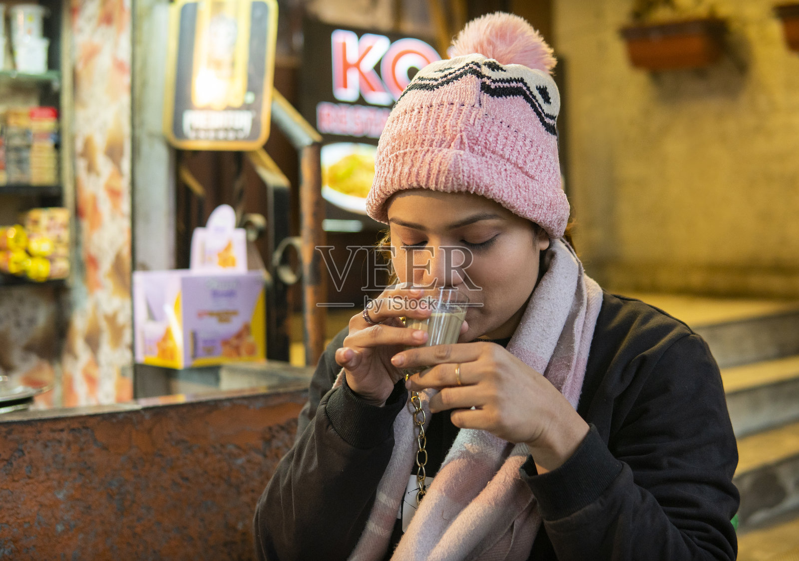 印度年轻女性在寒冷的冬天于路边茶摊喝马萨拉茶（chai）。照片摄影图片
