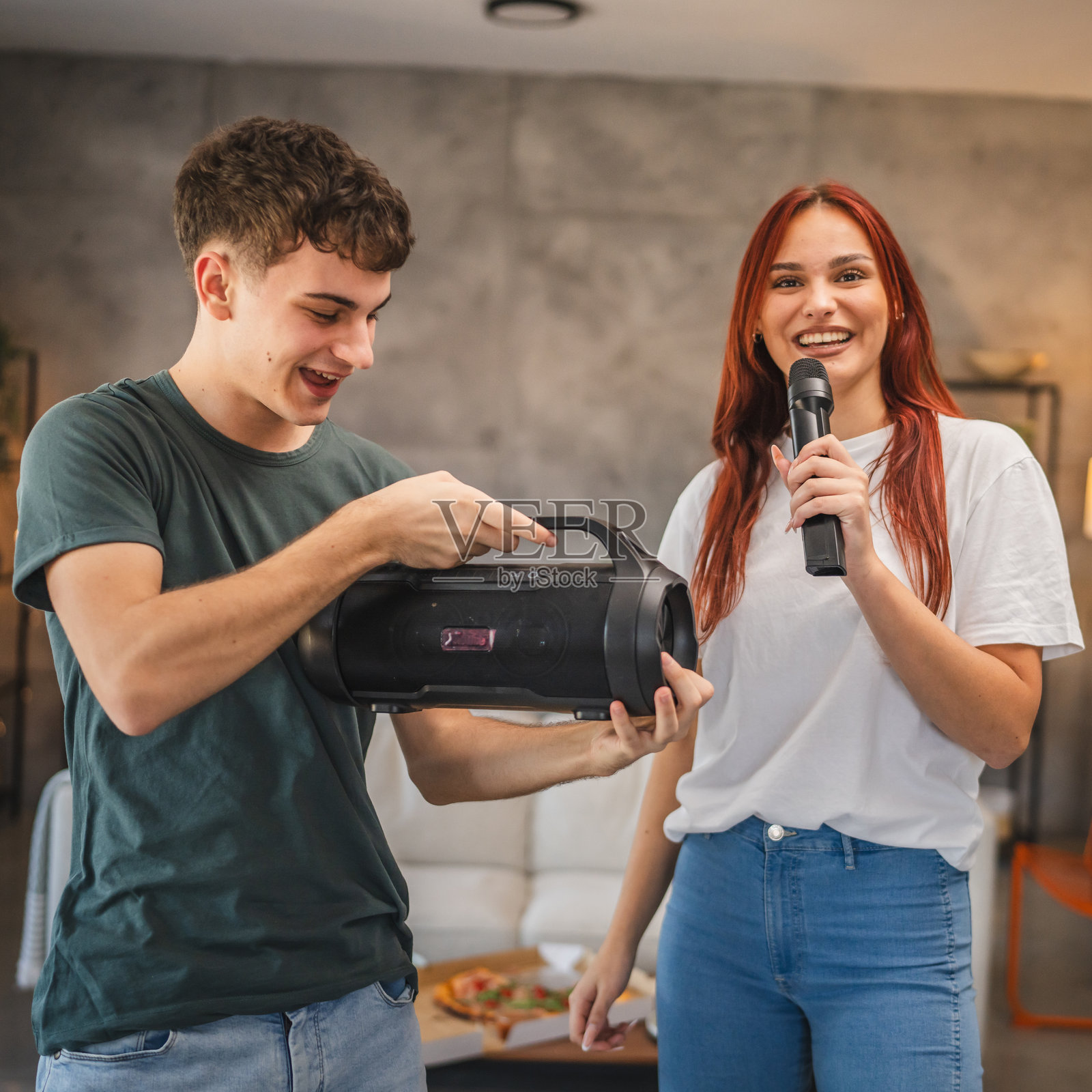 年轻情侣在家里举行卡拉OK之夜，一起跳舞和唱歌。照片摄影图片