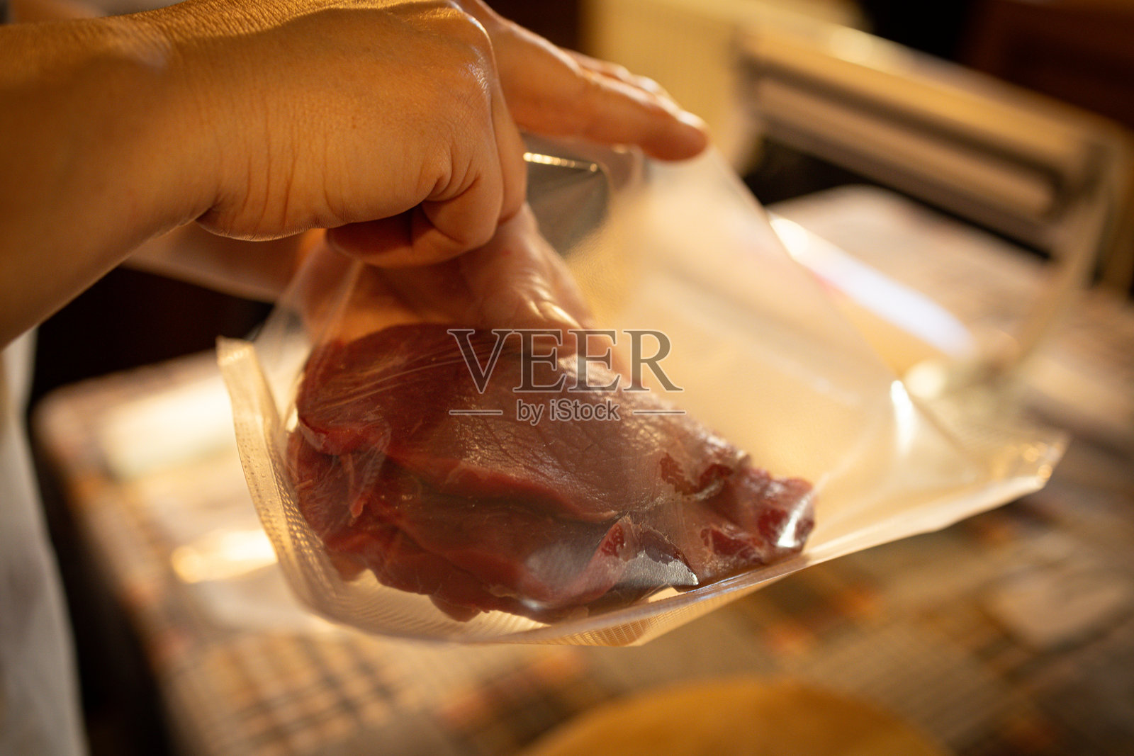 一位女性的手拿着塑料袋，正在为冷冻室包装肉类。照片摄影图片