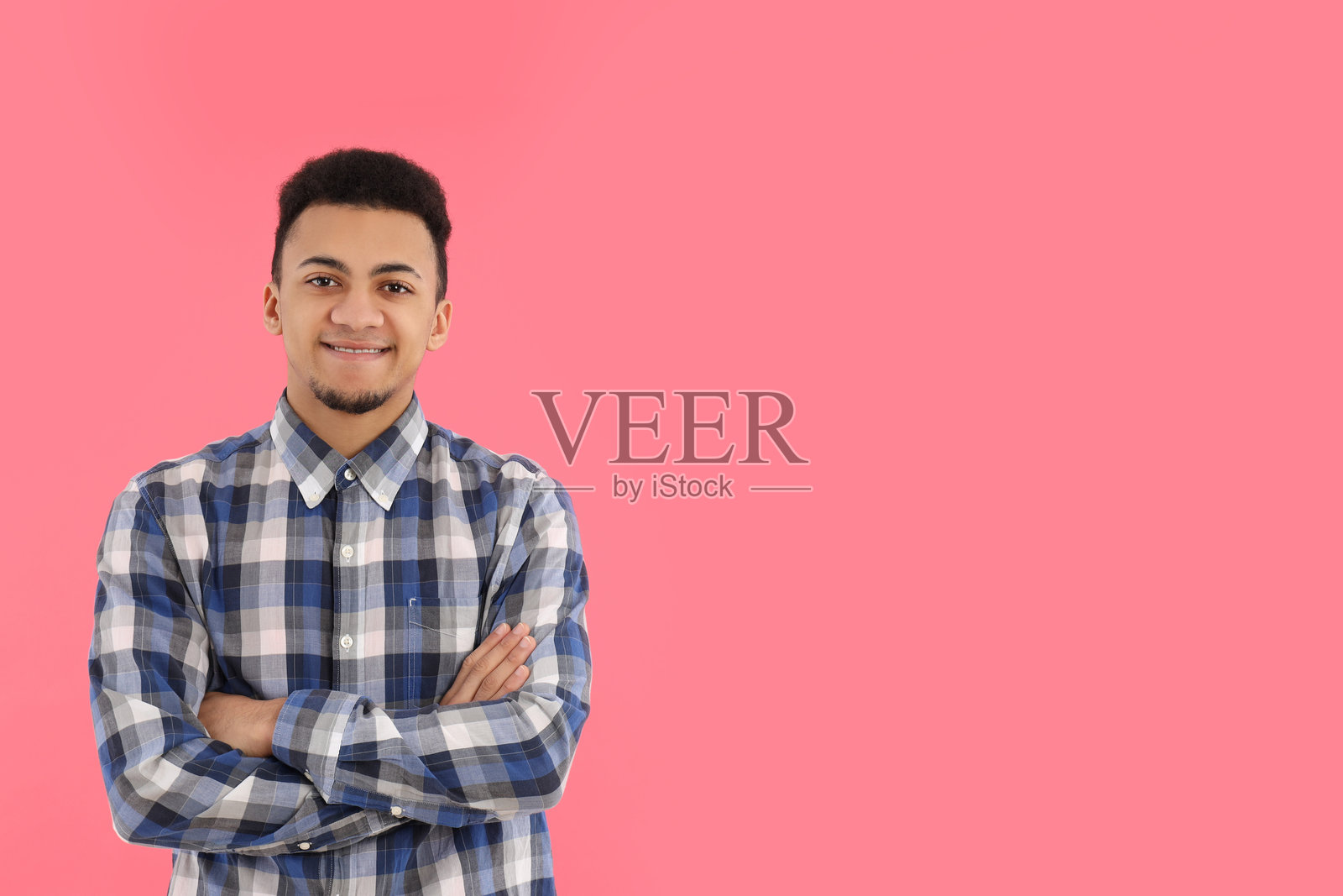 穿着格子衬衫的年轻男子在粉色背景前照片摄影图片