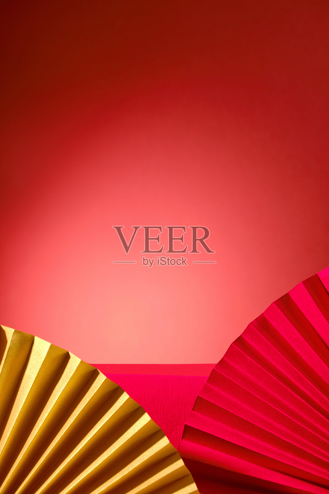 这幅图像展示了一个经典而优雅的背景，红色和黄色的纸扇与纯红色背景相映成趣，为展示产品或品牌信息创造了一个视觉上吸引人的框架。照片摄影图片