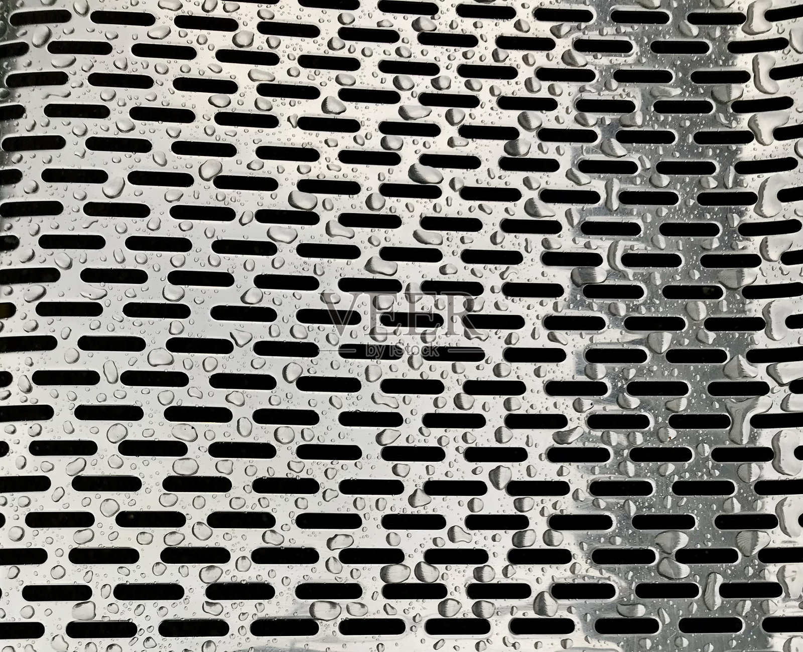 雨水落在光滑的金属上，反射出光线并突显出复杂的设计，融合了工业美学与自然元素。照片摄影图片