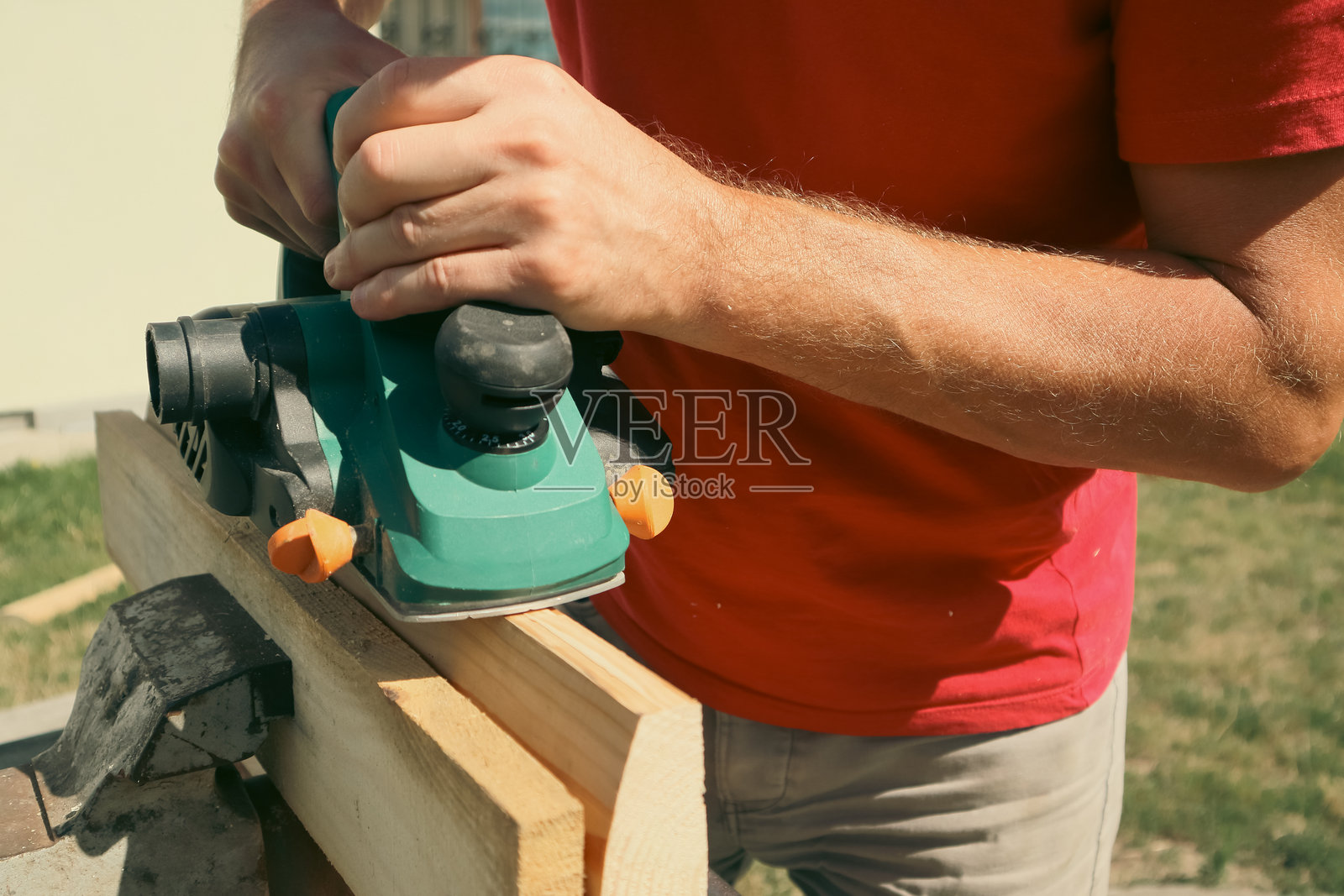 一名木匠正在使用电刨刨平一块木头。木匠正在刨平一块木板。照片摄影图片