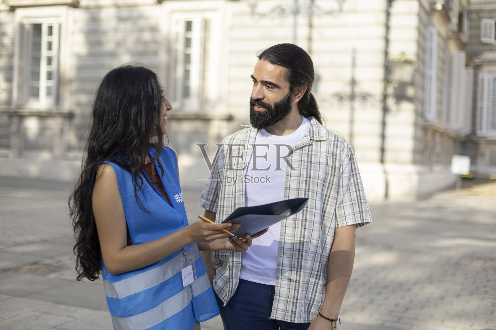 女志愿者拿着写字板在城市里与一名男子交谈照片摄影图片