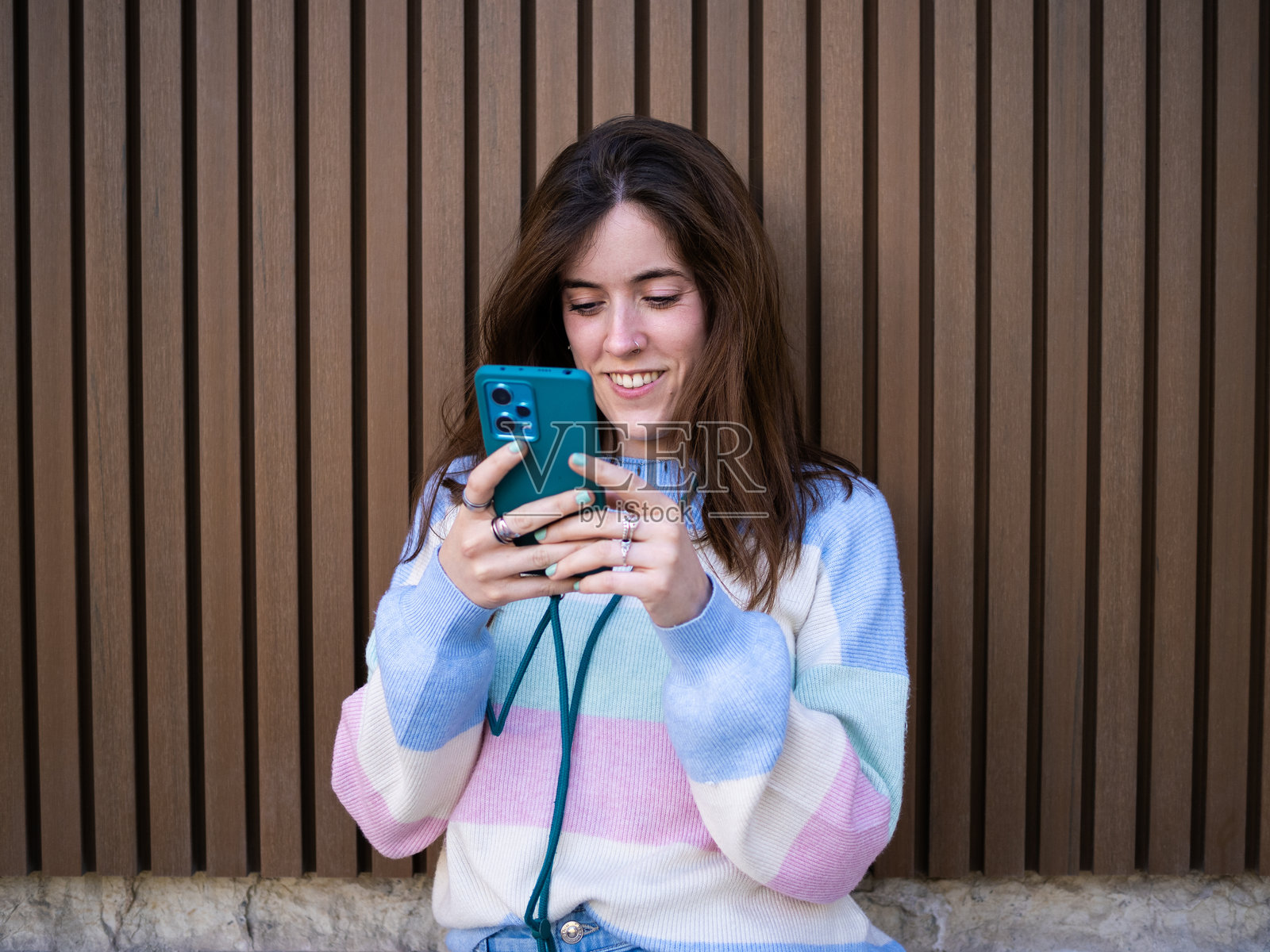 年轻女人靠在木墙上发短信微笑照片摄影图片