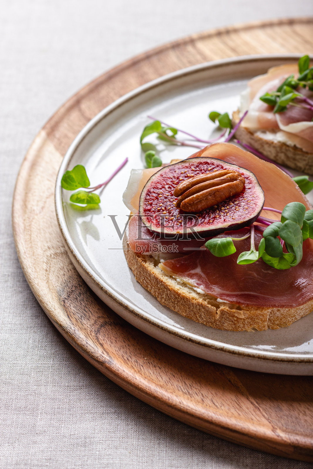 白面包片配年轻奶油奶酪、肉类、新鲜切片无花果和萝卜芽。照片摄影图片