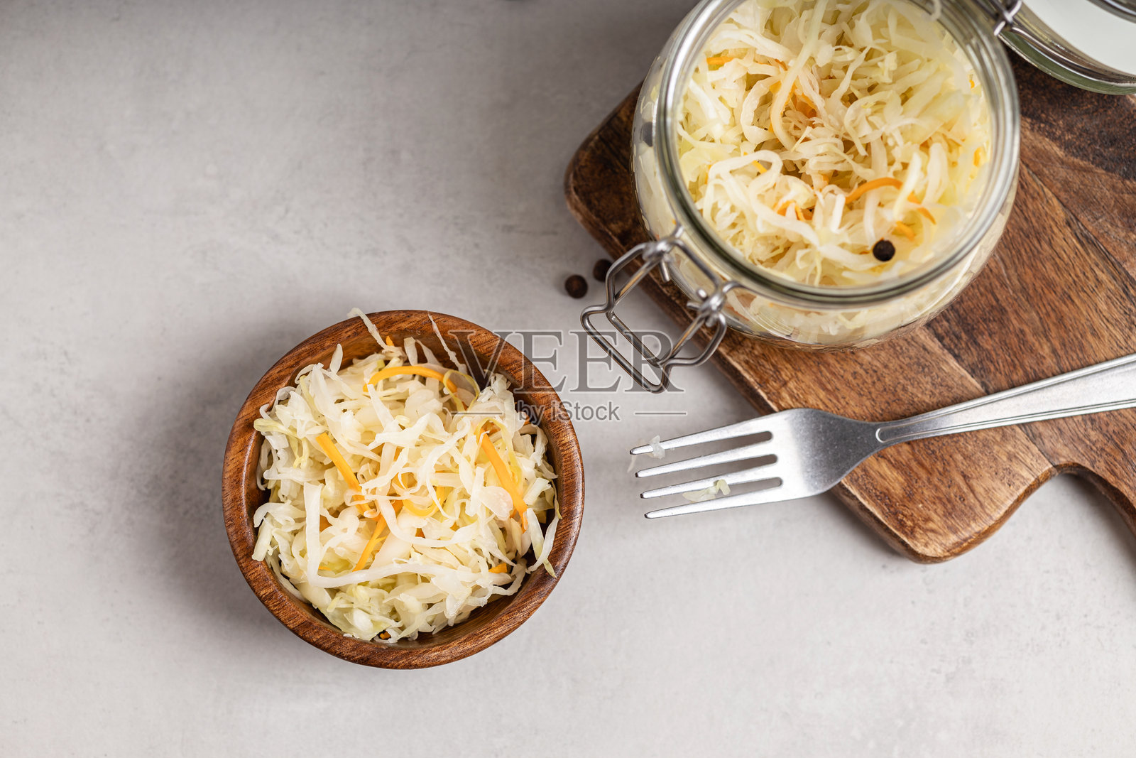 木碗和玻璃罐中的酸菜和胡萝卜。照片摄影图片