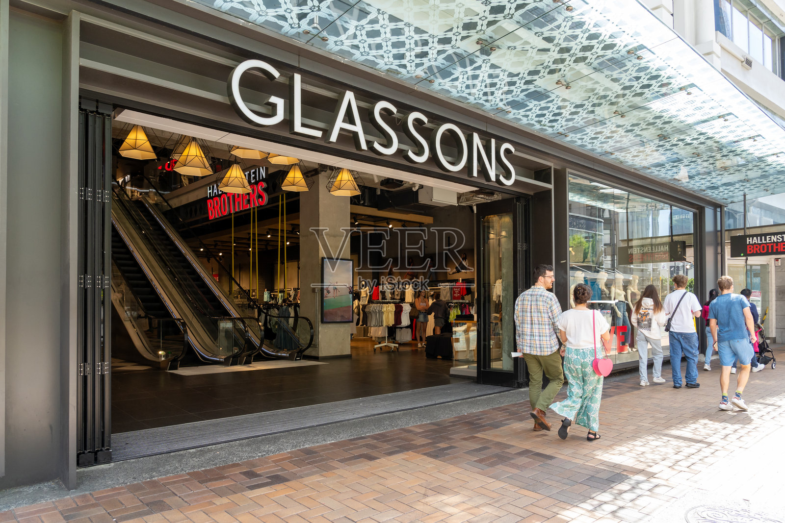 许多人在新西兰惠灵顿的Glassons商店前走过。照片摄影图片