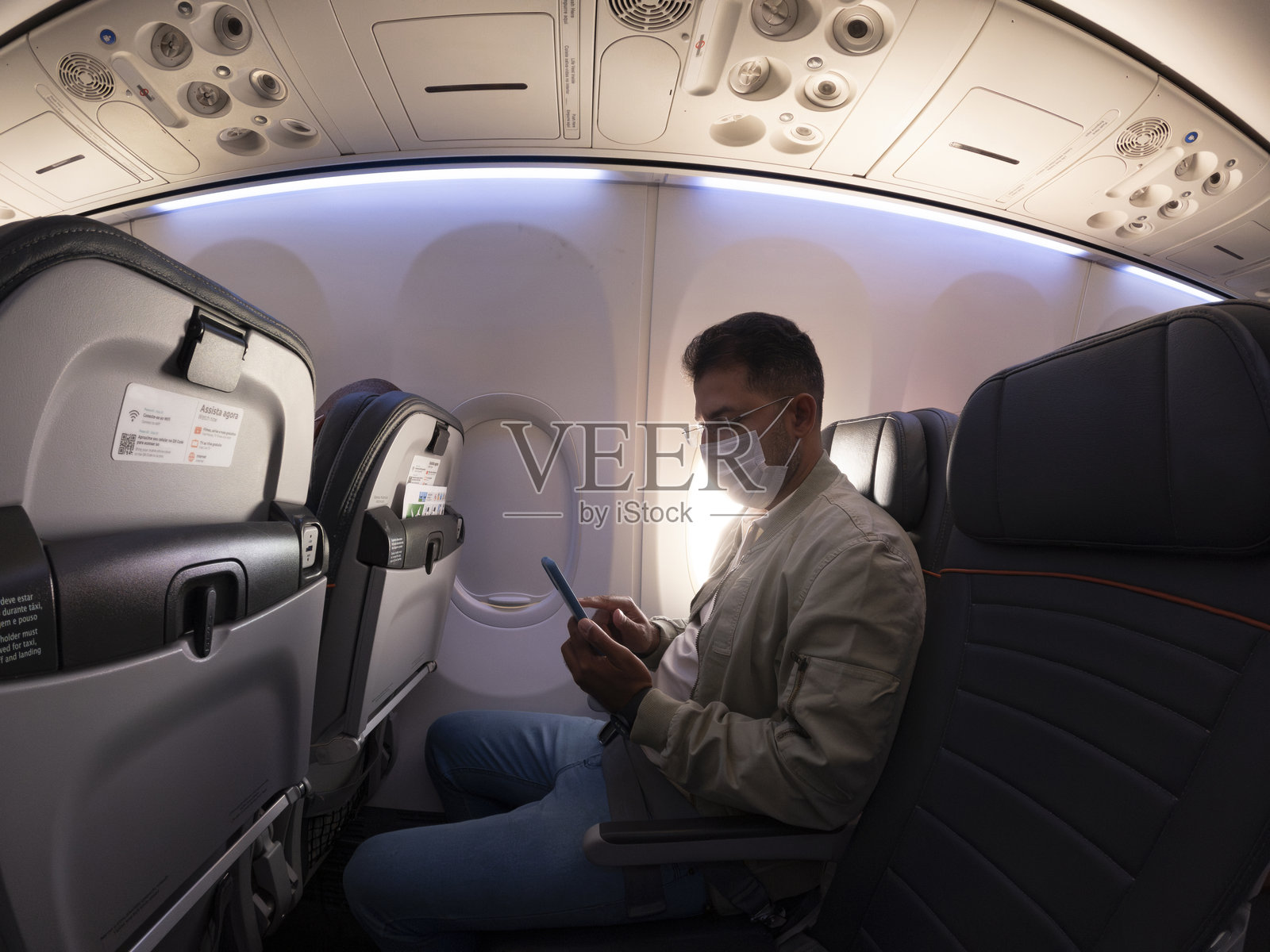 男人坐在飞机上使用智能手机照片摄影图片