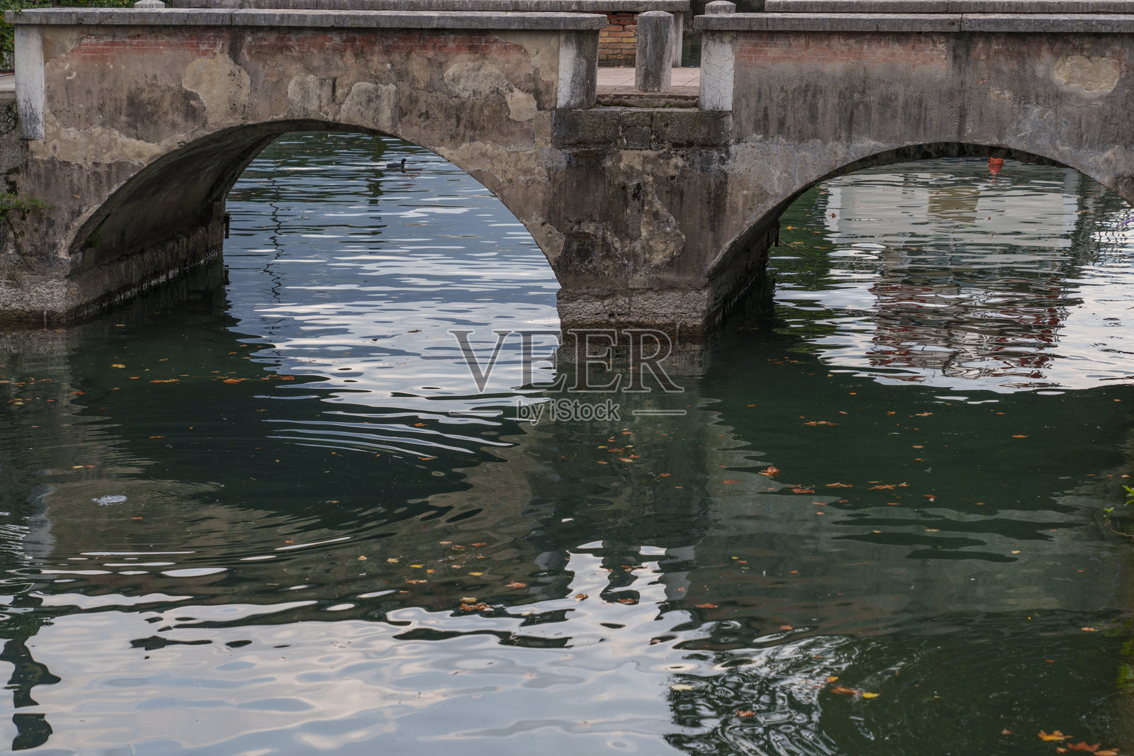 古老的混凝土桥横跨一条温和的河流。照片摄影图片