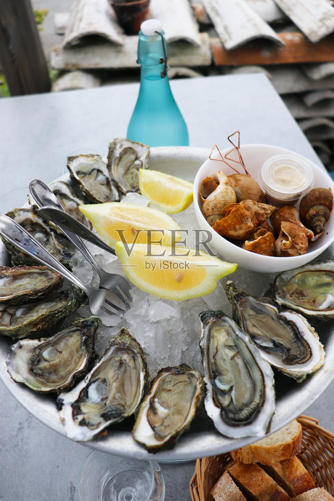 海鲜和白葡萄酒，搭配生蚝、柠檬和涂有黄油的面包的盘子和酒杯照片摄影图片