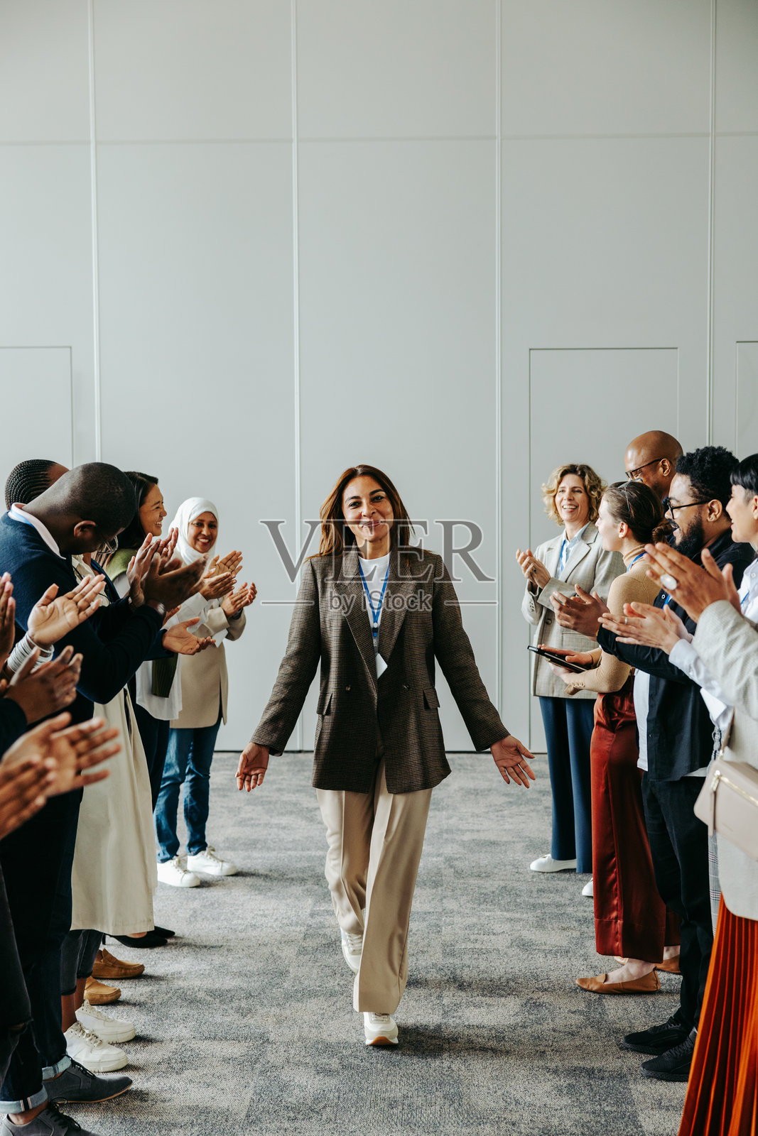 成功的女领导在现代办公室的商务会议上，在鼓掌支持的同事中行走照片摄影图片