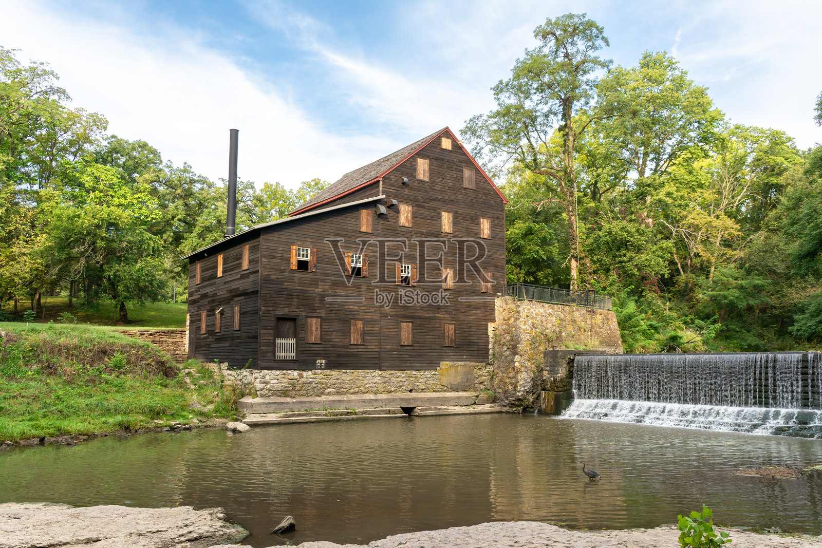 阳光明媚的夏日,位于美国爱荷华州马斯卡廷的野猫穴州立公园的1848年建成的松溪石磨坊照片摄影图片