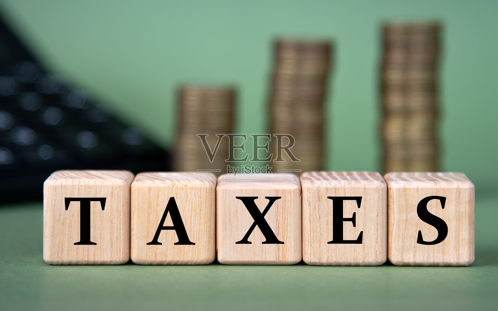 税收 - 木块上的字，背景有计算器和硬币照片摄影图片