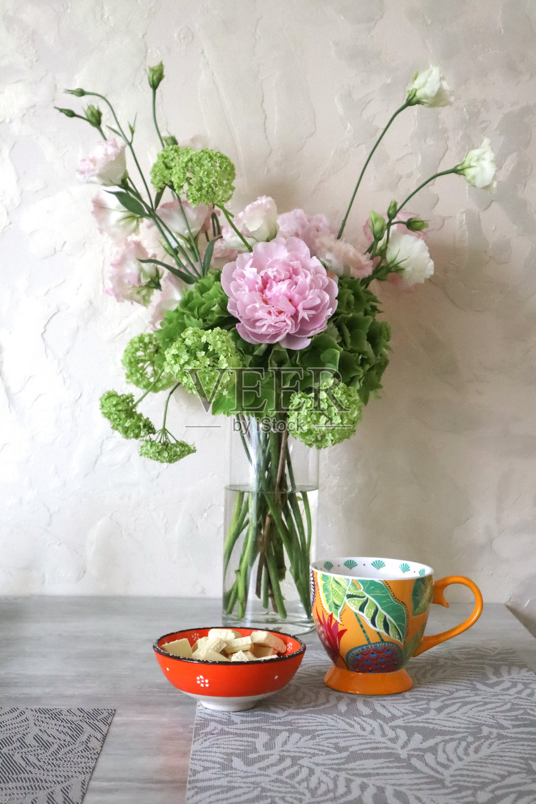 温柔的花束，包含绣球花、牡丹、忍冬和洋桔梗，放在桌子上的花瓶里。照片摄影图片