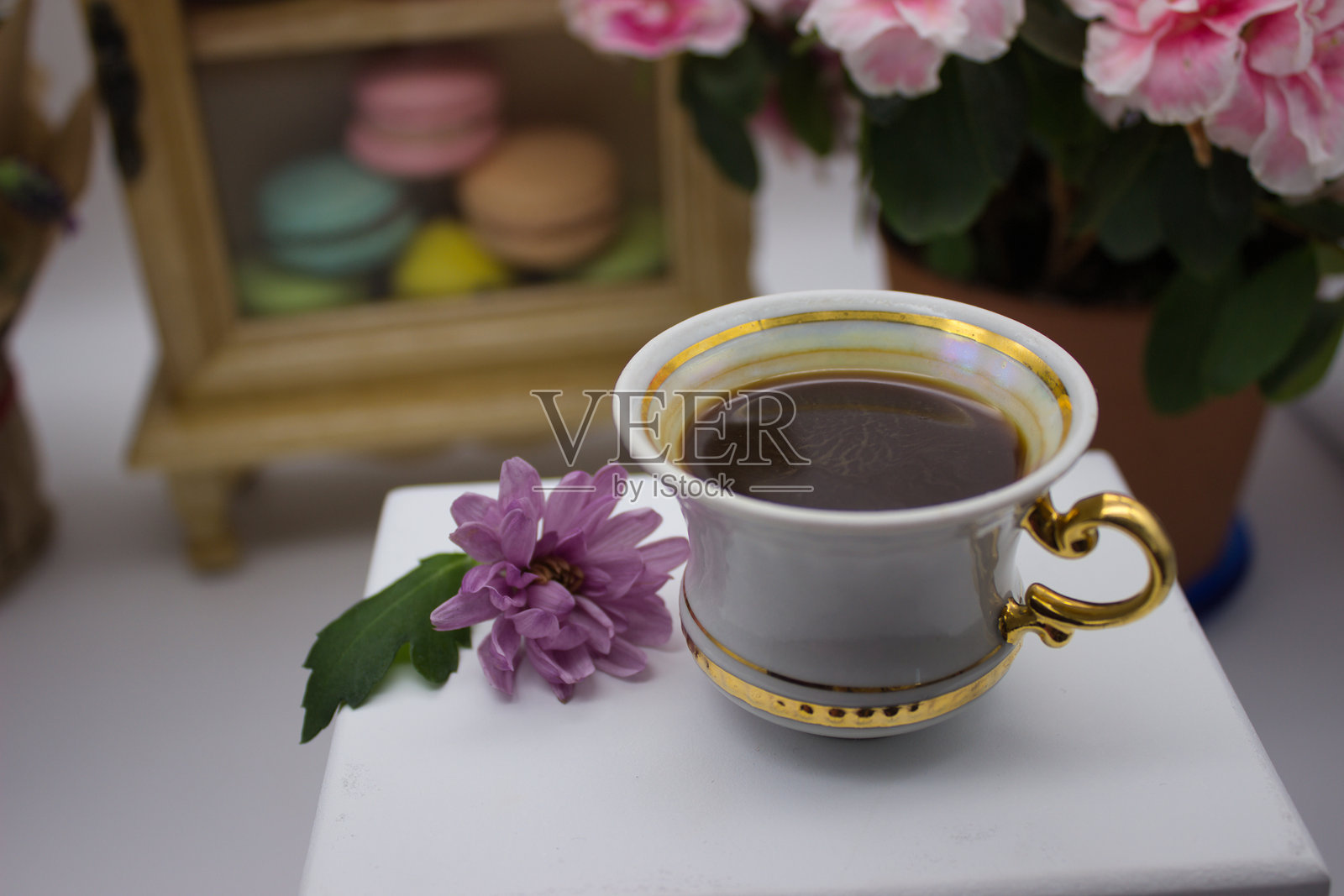 优雅的茶具摆设，配有鲜花和色彩缤纷的马卡龙照片摄影图片