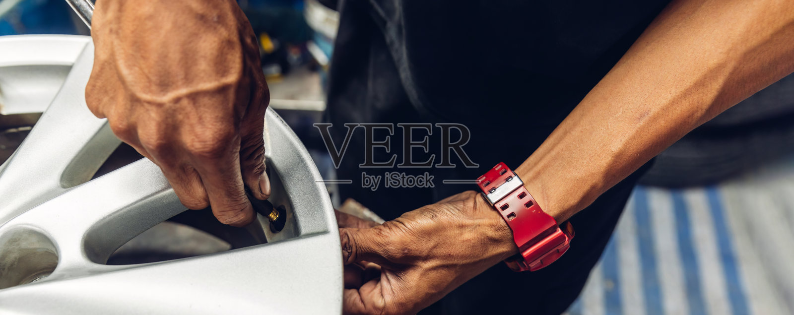 技师在车间使用轮胎拆卸器后，从轮辋上拆卸轮胎。工人们使用轮胎拆卸机将轮胎从轮辋上取下，技师正在修理轮胎。照片摄影图片