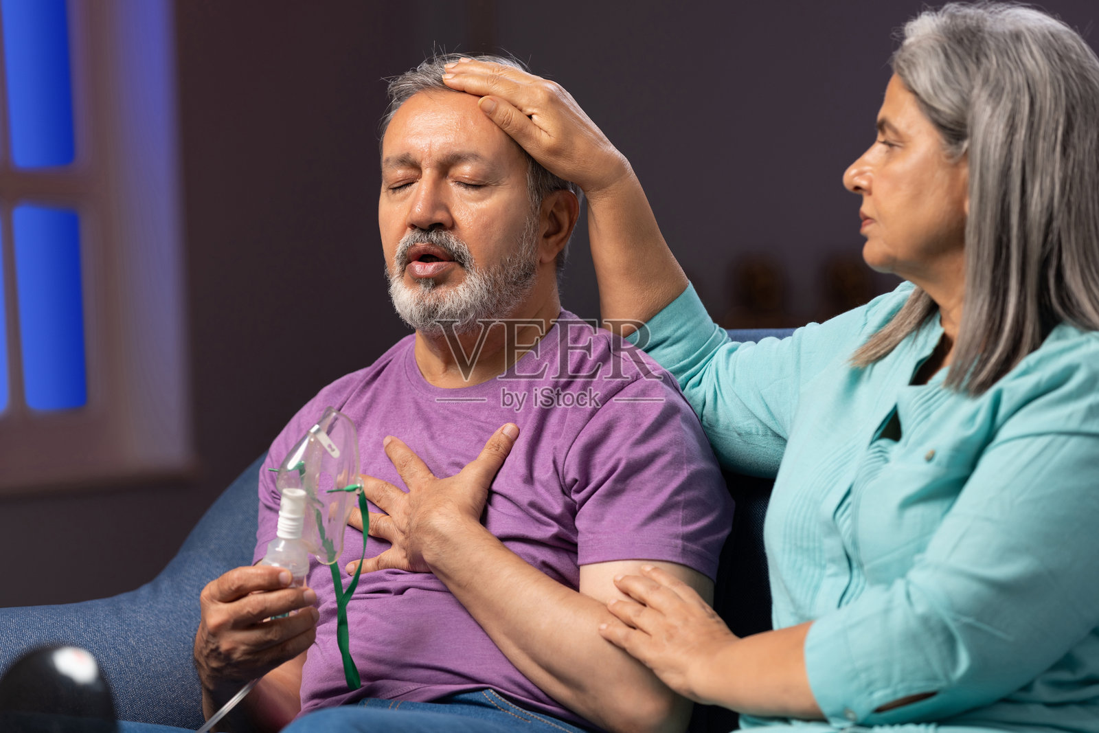 女人在沙发上给老公戴氧气面罩的照片照片摄影图片