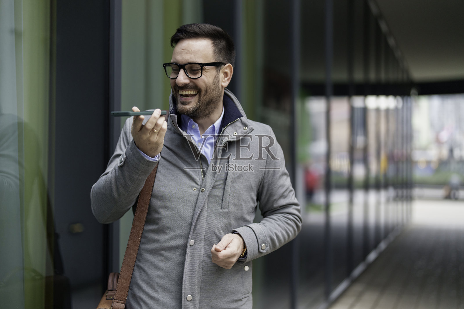 在户外用智能手机发信息的微笑的商人照片摄影图片