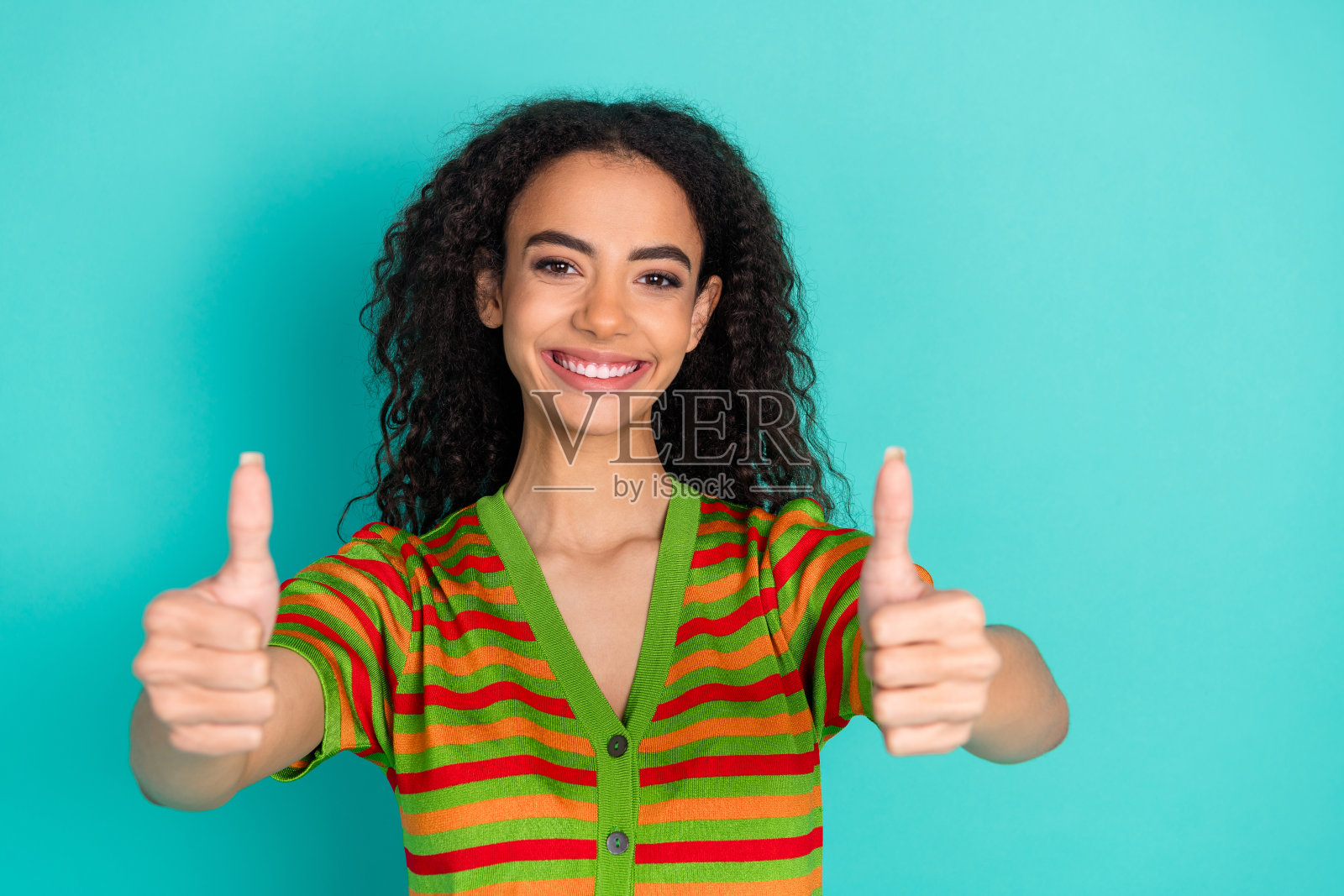 时尚条纹服装的可爱年轻女士在青色背景下竖起大拇指的照片肖像照片摄影图片