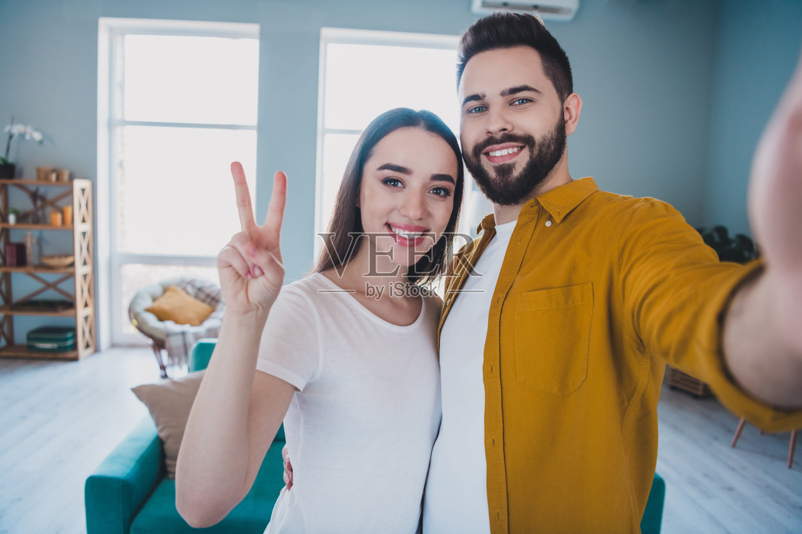 两名年轻合伙人在现代公寓内自拍并展示 V 字手势的照片照片摄影图片