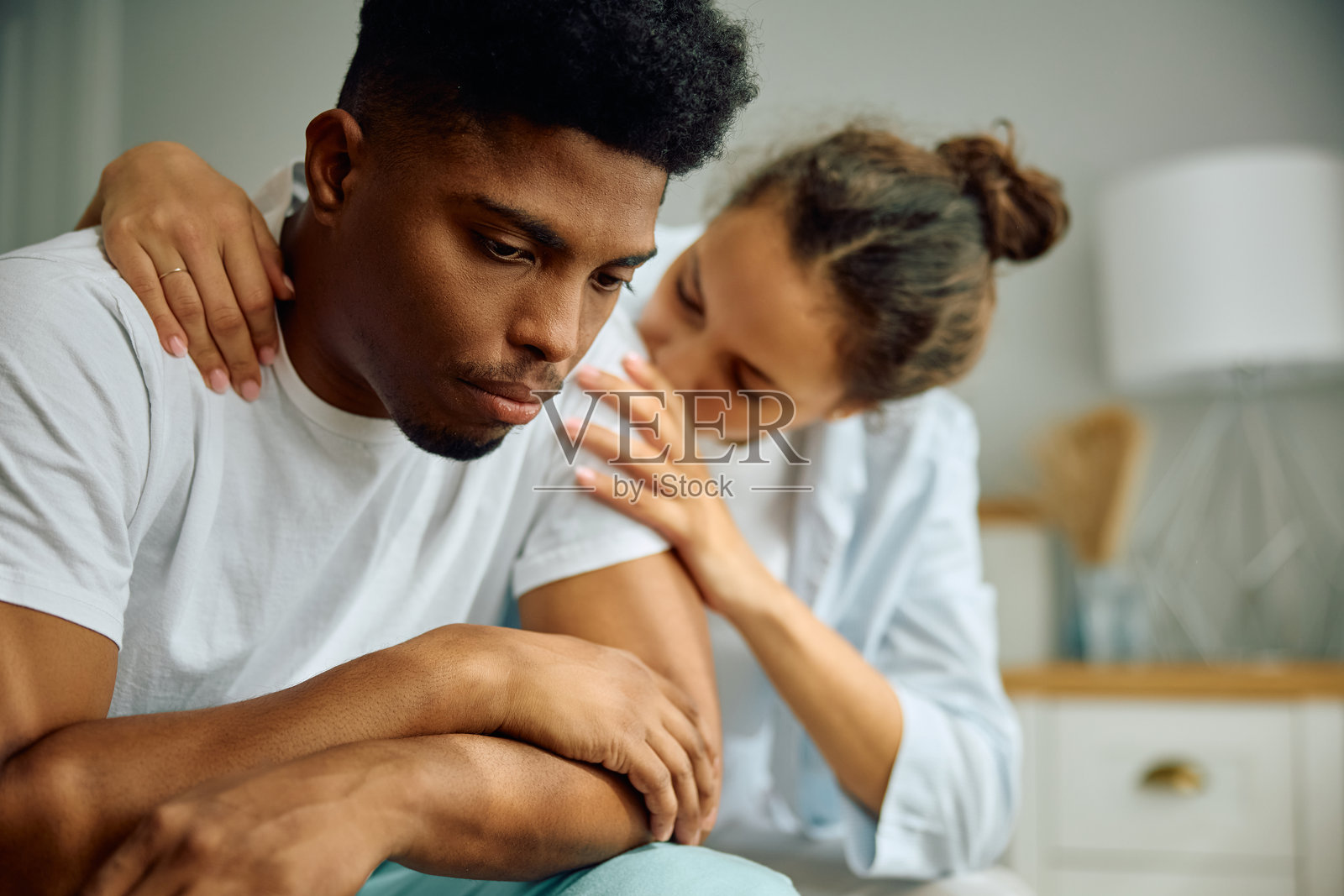 卧室里被女友安慰的悲伤黑人男人照片摄影图片